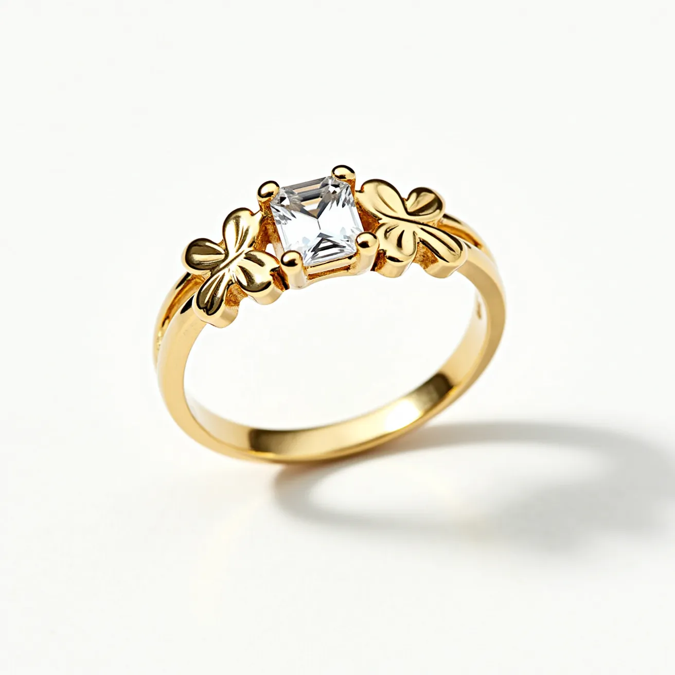 This midi ring is crafted from a gold-toned metal and features a central emerald-cut clear gemstone set in a prong setting. The stone is flanked by two decorative elements resembling clover leaves, adding an elegant and whimsical touch to the overall design. The smooth, polished band complements the shimmer of the central gemstone, and the ring does not appear to have any additional clasps or attachments, emphasizing its sleek and seamless style.