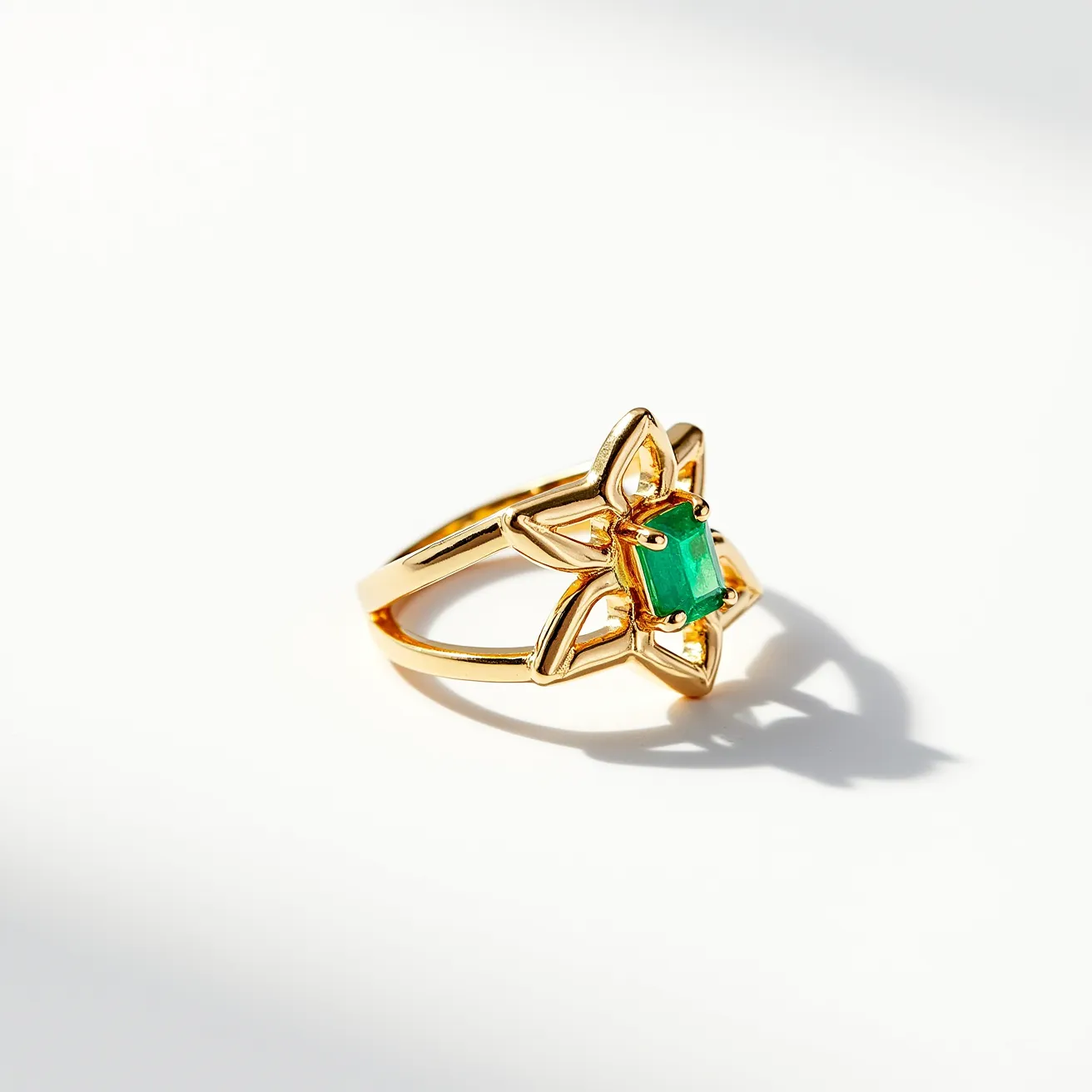 This midi ring features an intricate design in a gold-colored metal, forming a star-like shape that is both elegant and eye-catching. At the center of the ring, a vibrant emerald-cut green stone is set, secured with prongs that add a touch of sophistication to the overall appearance. The open design of the band adds to the delicacy and style of the piece. The combination of the gold metal and the green stone creates a visually striking contrast, making it a standout accessory.