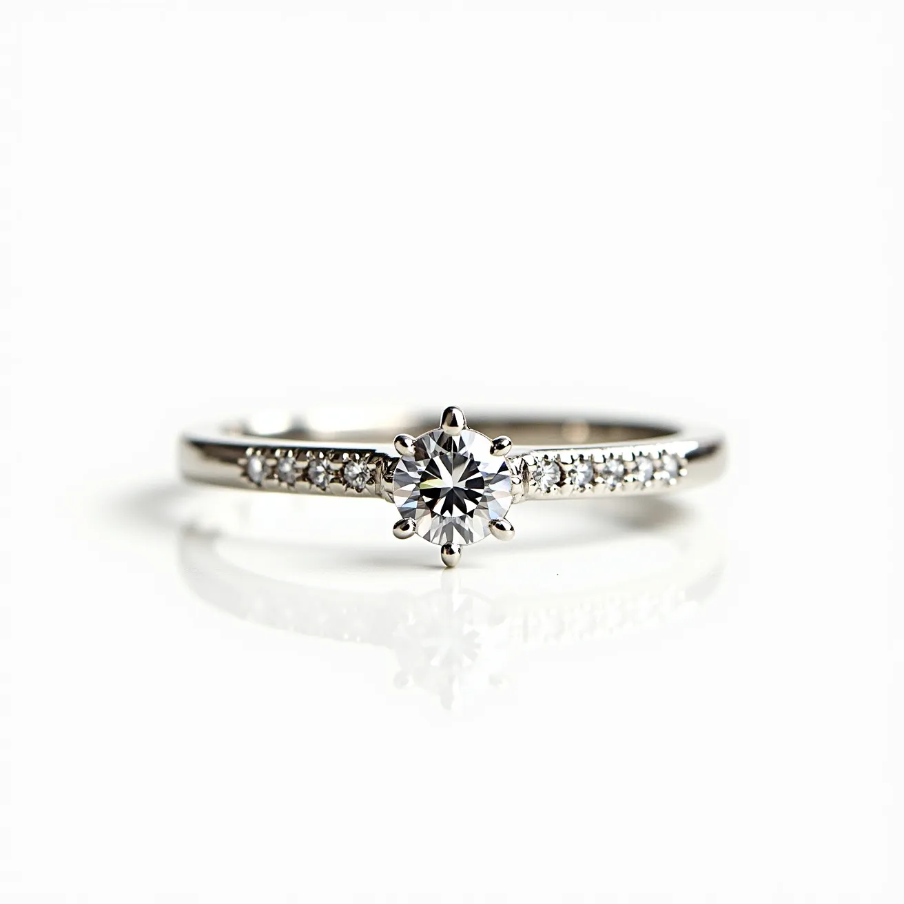 This moissanite promise ring features a central round-cut moissanite gemstone, elegantly set in a six-prong setting that securely holds the stone and enhances its brilliance. The band is crafted from what appears to be a polished white metal, likely white gold or platinum, known for its lustrous finish and durability. Adorning the band on either side of the central stone are smaller round moissanite gems, set in a pavé style that creates a continuous sparkle across the ring. The prongs and band merge seamlessly, providing both aesthetic appeal and functionality in securing the stones. There is no visible clasp, as is typical for rings, ensuring a sleek, uninterrupted design.