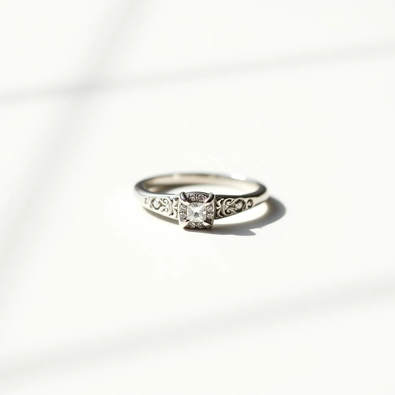 This moissanite promise ring features a brilliant square-cut moissanite stone set in an intricate mounting. The band is crafted from a polished metal, likely white gold or platinum, and showcases delicate scrollwork engravings on either side of the central stone. The moissanite is held securely in a prong setting, allowing maximum light to enter and enhance its sparkle. The ring's design combines elegance and intricate detailing, making it a stylish symbol of commitment.