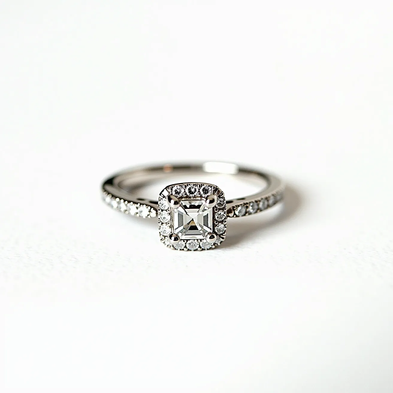 This moissanite promise ring features a central square-cut moissanite gemstone, set in a halo of smaller round moissanite stones that enhance its brilliance. The band is crafted from a lustrous metal, likely white gold or platinum, designed to complement the brightness of the stones. The side of the band is adorned with additional small moissanite stones, adding a touch of elegance and continuous sparkle. The setting appears to be a prong setting, which securely holds the center stone in place while allowing maximum light to enter, enhancing its radiance. Overall, the ring exudes a timeless and elegant charm, ideal for symbolizing a heartfelt promise.