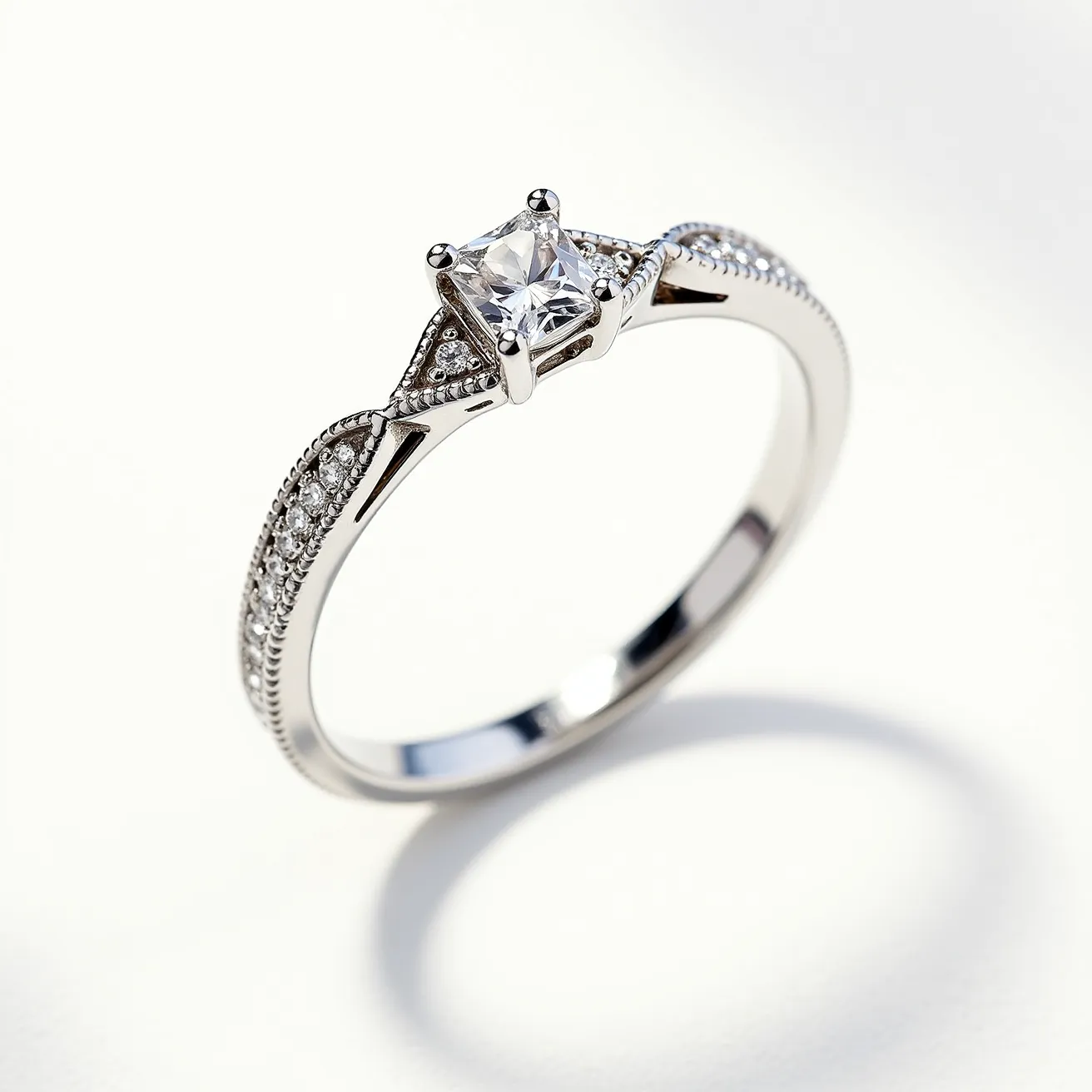 This moissanite ring features a centerpiece moissanite gem in a classic solitaire setting with a square cut, held securely by four prongs. The band is likely made of a lustrous metal, such as white gold or platinum, enhancing the ring's elegant appearance. Along the shoulders of the band, there are small, round moissanite accent stones set into the metal in a pave style, adding additional sparkle and sophistication. The combination of the central stone and accent stones creates a harmonious and eye-catching design, ideal for someone seeking timeless elegance.