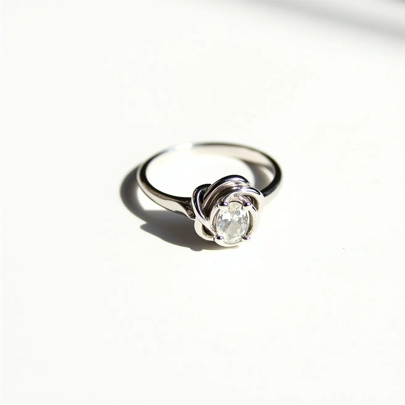 This moissanite ring features a lustrous oval-cut moissanite gemstone prominently set at its center. The stone is secured using a prong setting, which not only holds it firmly in place but also allows maximum light to pass through, enhancing its sparkle. The band appears to be crafted from a polished, likely metallic material, possibly white gold or platinum, adding to the ring's elegant appearance. Surrounding the moissanite is a distinctive twisted metal design that adds a unique and intricate touch to its overall style. The ring does not appear to have any additional clasps, focusing the attention on the central gemstone and its setting.