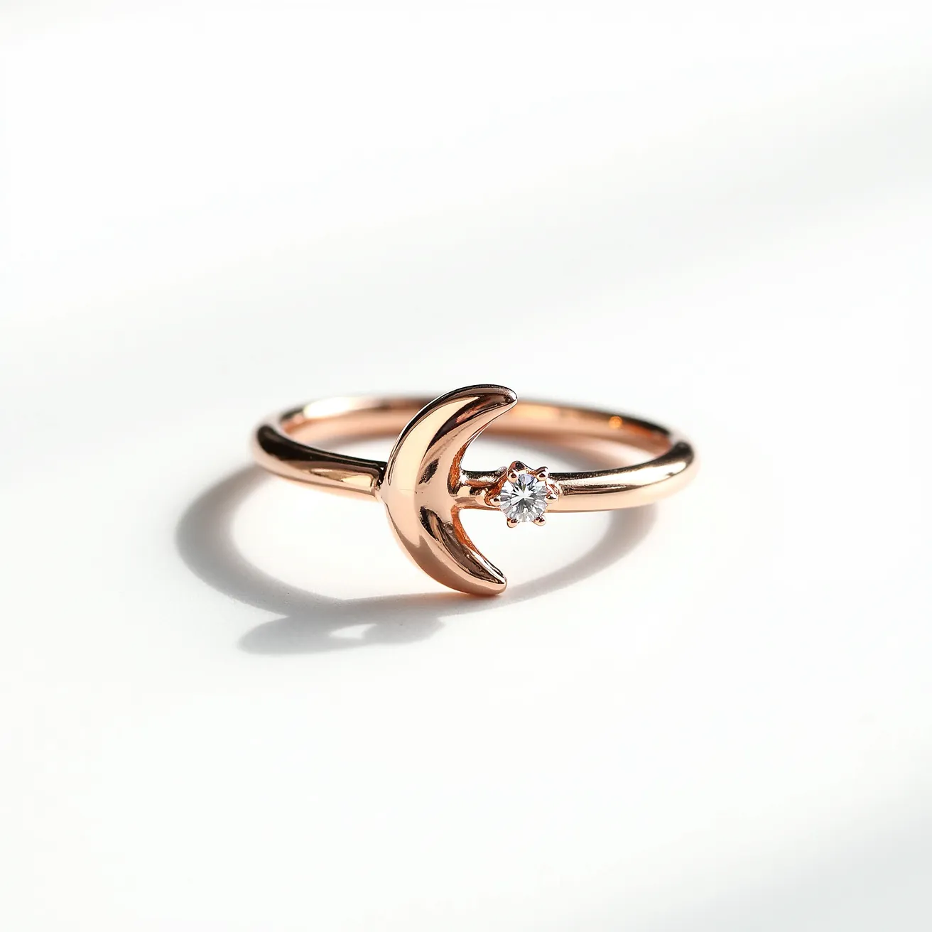 This moon ring features a sleek and delicate design, crafted in a rose gold band that exudes a warm and elegant glow. The centerpiece is a crescent moon motif, artistically integrated into the band, symbolizing subtle celestial beauty. Adjacent to the crescent is a brilliant-cut diamond, securely held in a prong setting that enhances its sparkle and complements the lustrous finish of the gold. The ring's minimalist yet sophisticated style makes it a versatile accessory, perfect for every occasion.