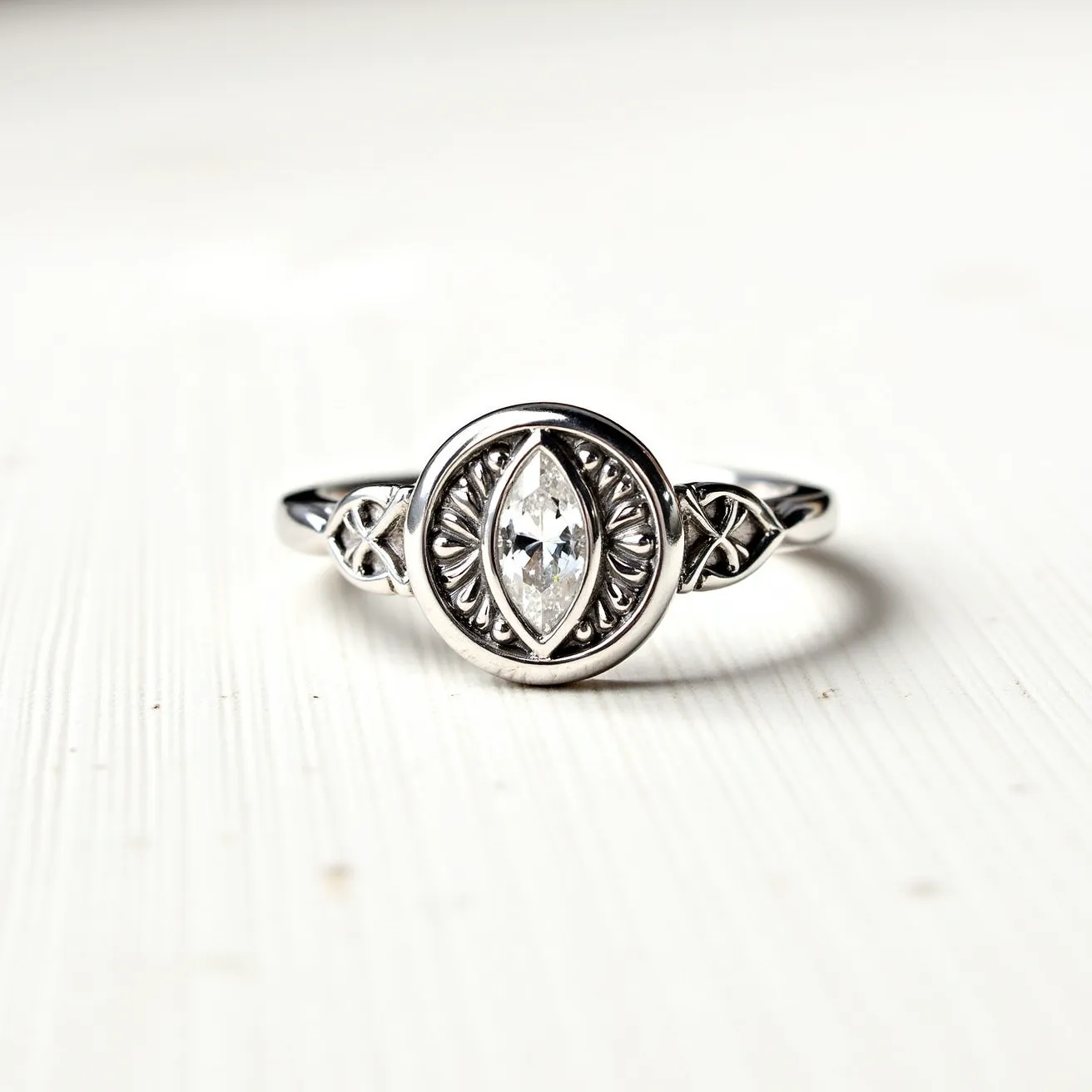 This moon ring features a central marquise-cut clear gem, which is elegantly set in a bezel setting. The gem is framed by a circular metallic border that may be crafted from a silver-tone metal, providing a sleek contrast to the sparkling stone. The design incorporates intricate detailing and symmetrical patterns reminiscent of celestial motifs. The band displays delicate filigree work, enhancing the overall aesthetic and adding a touch of sophistication to the piece.