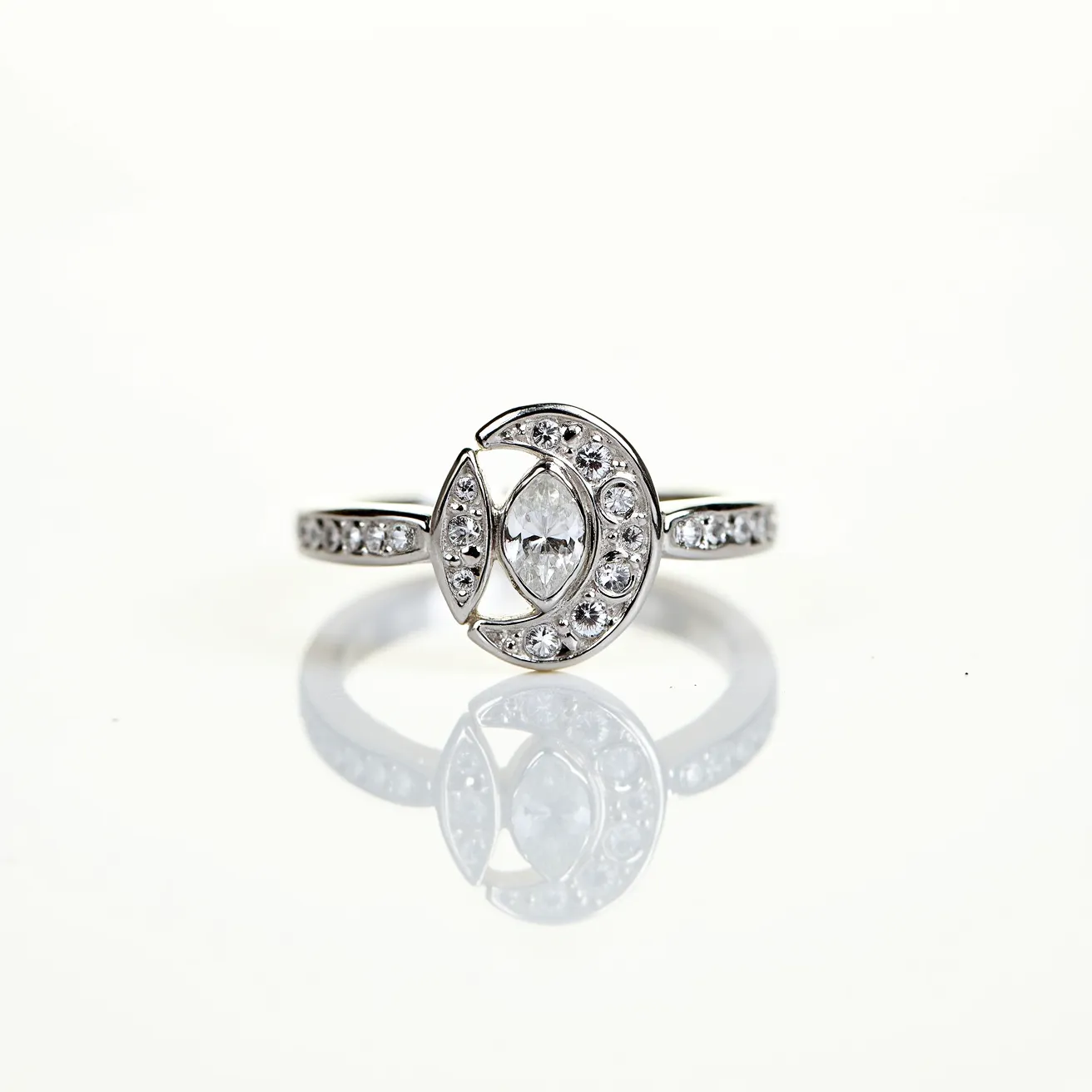 This moon ring features a sleek, metallic band likely crafted from silver or white gold, enhancing its elegant design. The centerpiece showcases a marquise-cut clear gemstone set in the center of a circular design, symbolizing a crescent moon with sparkling accents. Surrounding the main stone are smaller round stones, either diamonds or diamond-like gems, meticulously embedded into the crescent setting, adding a beautiful shimmer. The band is also adorned with similar stones, echoing the celestial motif. The setting is smooth and flush, holding the stones securely in place and offering a seamless look.