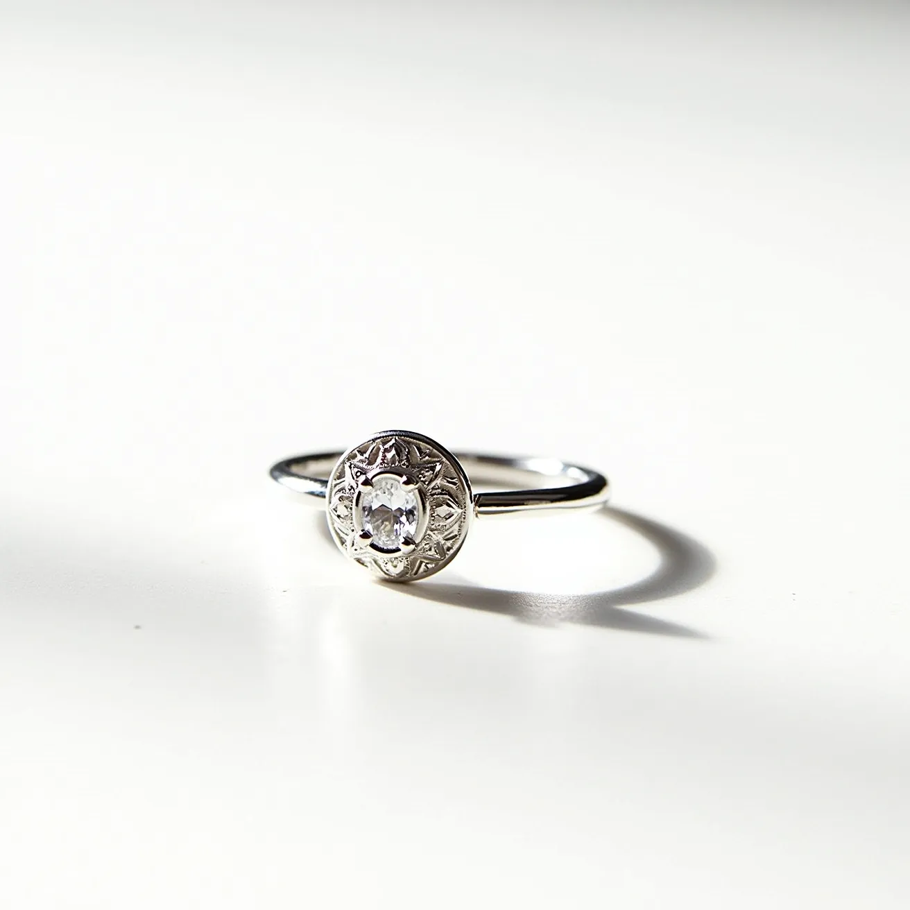 This moon ring features a delicate, circular design crafted from a shiny metal, likely silver, which lends it an elegant appearance. At the center, a small, round gemstone is set; it seems to be a clear stone, such as a diamond or cubic zirconia, which is cut in a manner that maximizes its brilliance. The setting is a bezel style, where the metal encircles the stone, offering both security and a sleek, modern look. The band is slim and smooth, allowing the central design to stand out as the focal point.