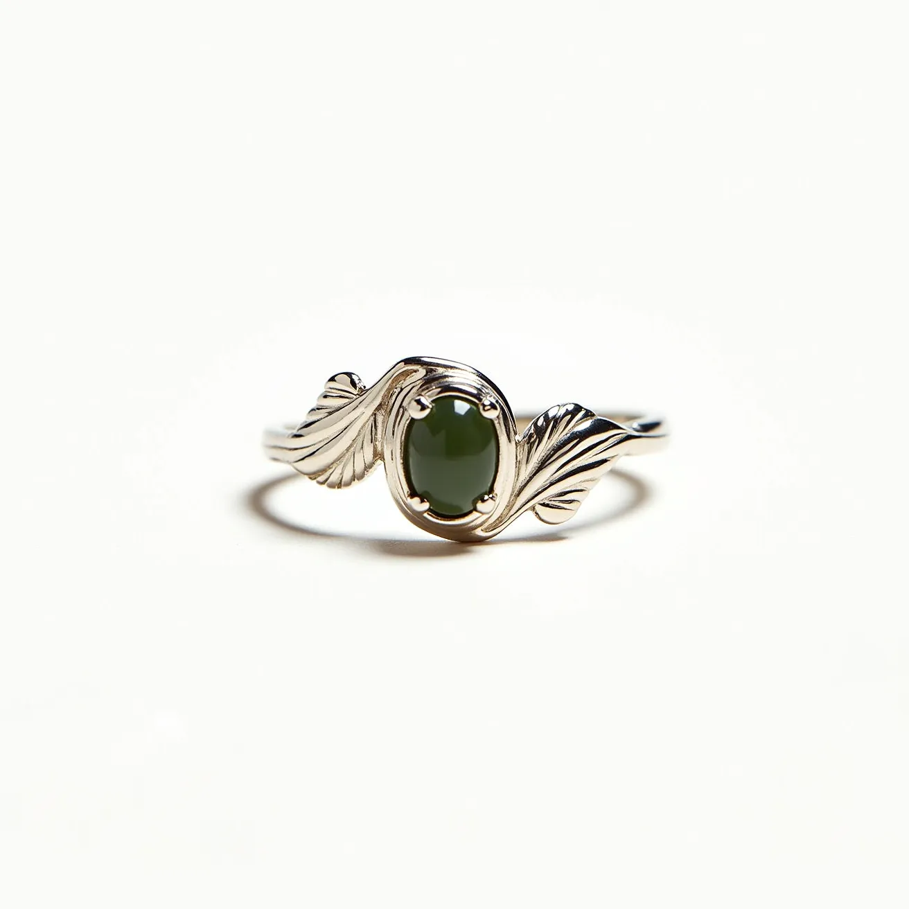 This moss agate ring features a polished oval moss agate as its central gem, set within an elegant four-prong setting that securely holds the stone in place. The ring band is intricately designed with a leaf motif on either side of the gem, crafted from a silver-colored metal that enhances the organic appearance. The leaves gracefully curve around the stone, adding a unique and artistic touch to the overall design. The smooth band provides a comfortable fit, making it suitable for everyday wear. The combination of the natural green tones in the moss agate with the glossy metal finish offers a harmonious and earthy aesthetic.