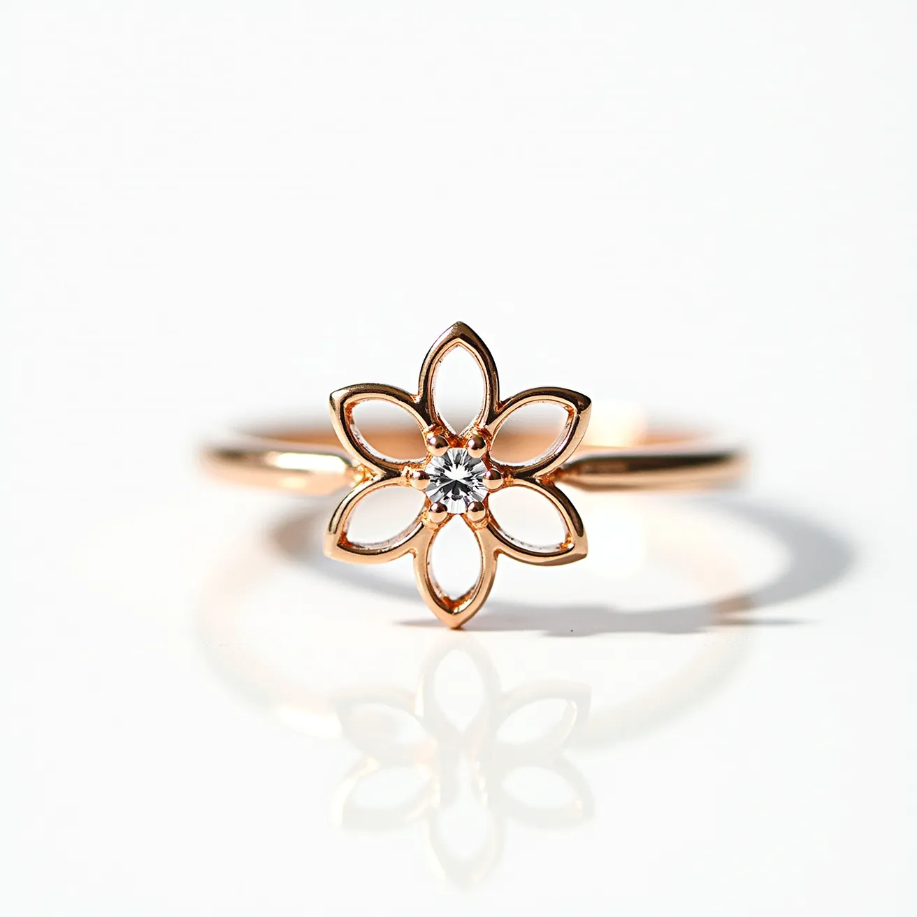 This mother's ring features a delicate and elegant design crafted in what appears to be rose gold. The central focus is a floral shape with intricately open petals that create a captivating and airy pattern. At the center of the flower, a small, round-cut diamond or diamond-like gem is securely set, adding a hint of sparkle. The slender band complements the elegance of the floral motif without any additional clasps or attachments, resulting in a seamless and minimalist aesthetic.