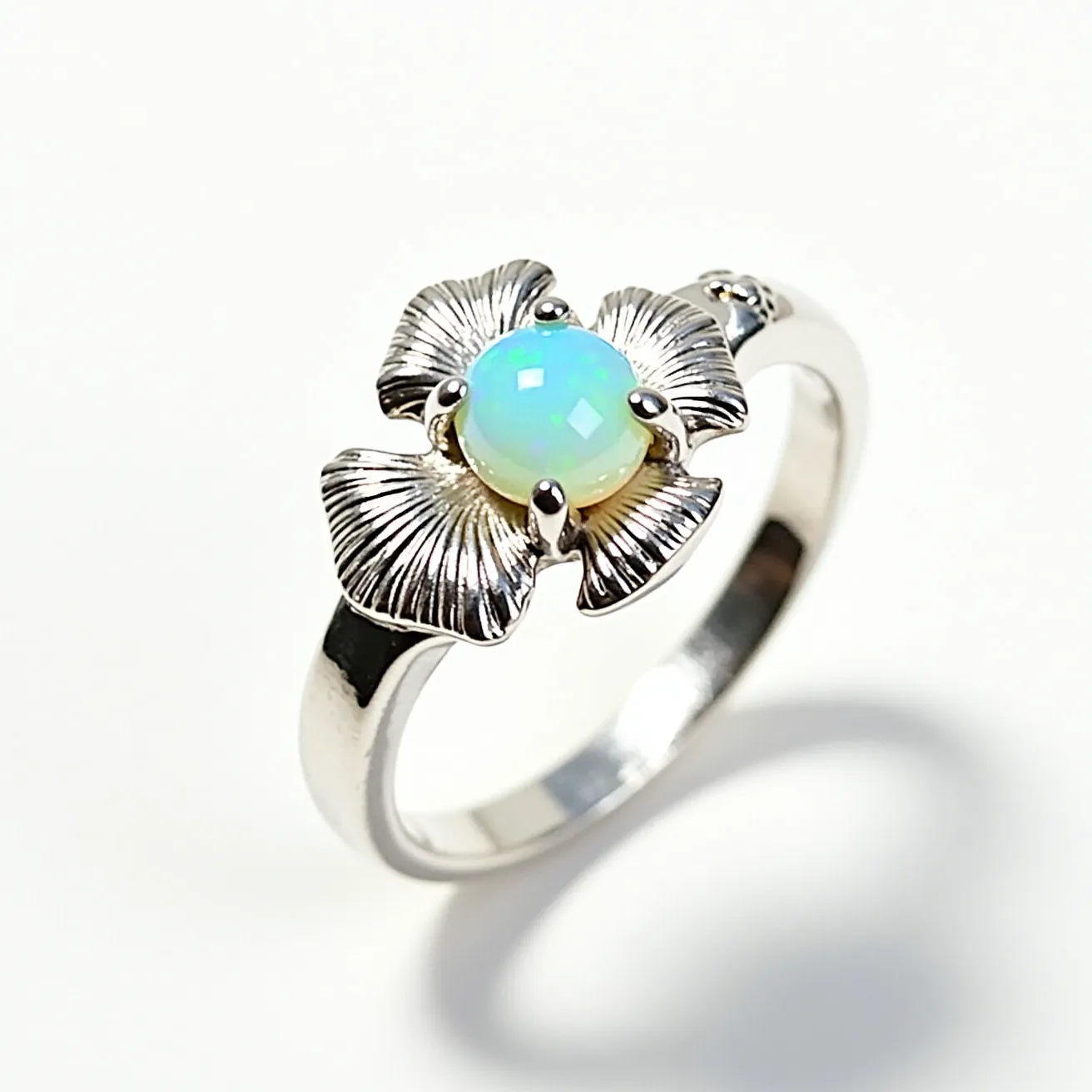 This mushroom ring features a polished metal band, likely made of silver, with its centerpiece resembling the whimsical shapes of a mushroom's cap. The ring is adorned with a central opal gemstone, cut in a cabochon style that enhances its iridescent play of colors. The opal is set with prongs, securely holding it in place. The mushroom-inspired design includes textured elements that mimic gills, adding artistic detail and dimension to the overall look.