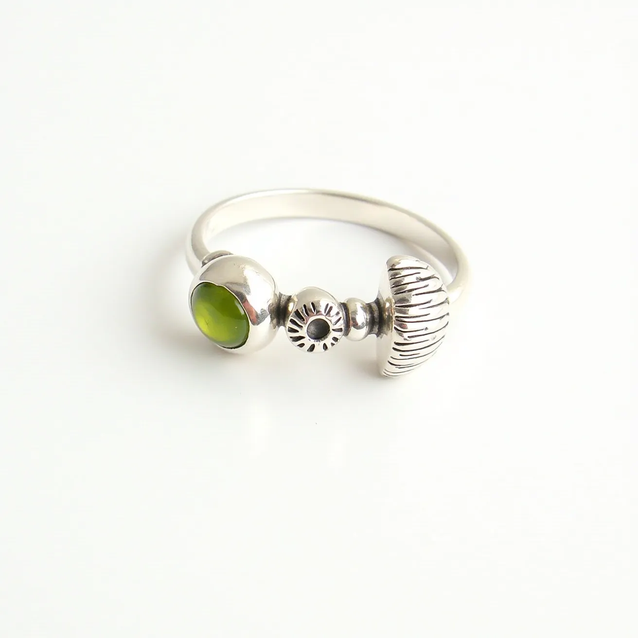 This mushroom ring features a delicate design crafted from a silvery metal, most likely sterling silver, showcasing intricate details that resemble the cap and stalk of a mushroom. Alongside the mushroom motif, there is a small, round bezel-set gemstone of vibrant green, possibly peridot or another green gem, adding a pop of color and contrast to the piece. The gemstone is smooth with a cabochon cut, enhancing its glossy appearance. The simplicity of the band complements the whimsical theme of the ring, allowing the decorative elements and gemstone to stand out beautifully.