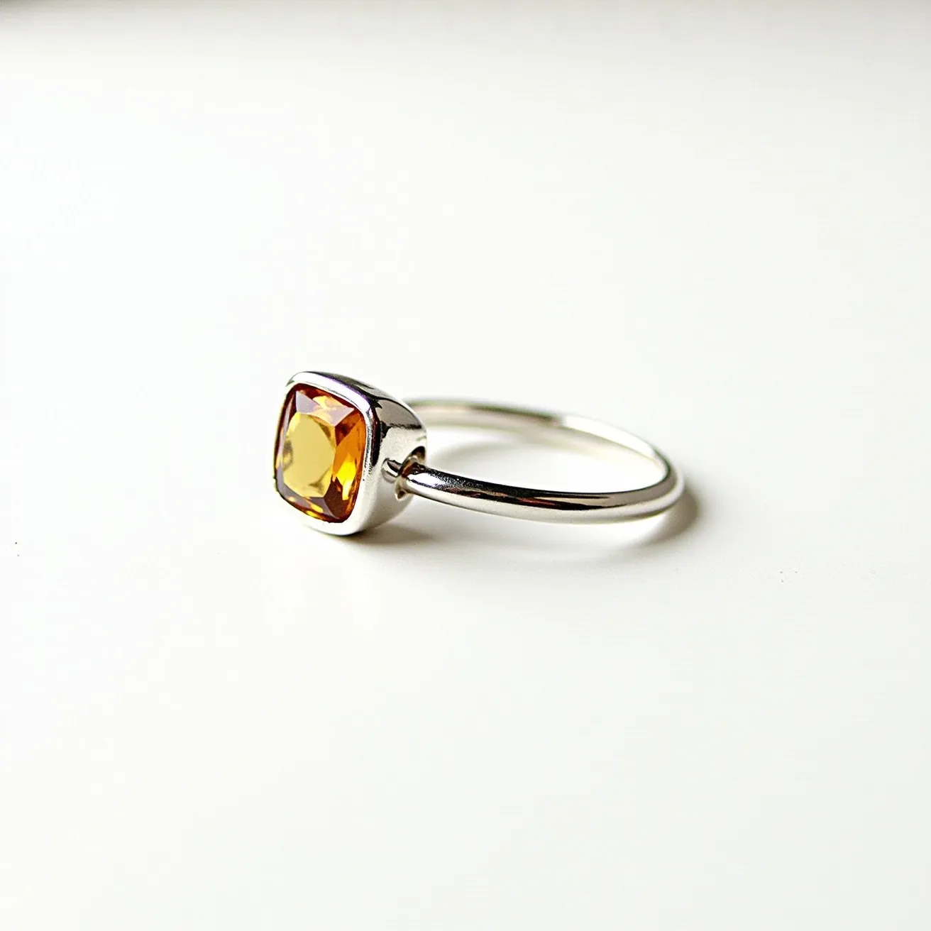 This November birthstone ring features a striking citrine gemstone, renowned for its warm, golden-yellow hue. The stone is cut into a cushion shape, offering a classic and refined appearance that enhances its natural brilliance. It is securely set in a bezel setting, providing both protection and a modern aesthetic. The ring itself is crafted from a polished metal, likely sterling silver, which complements the citrine’s vibrant color and adds a sleek, contemporary touch to the design. The simple band highlights the elegance of the gemstone, making it a stylish and timeless accessory.