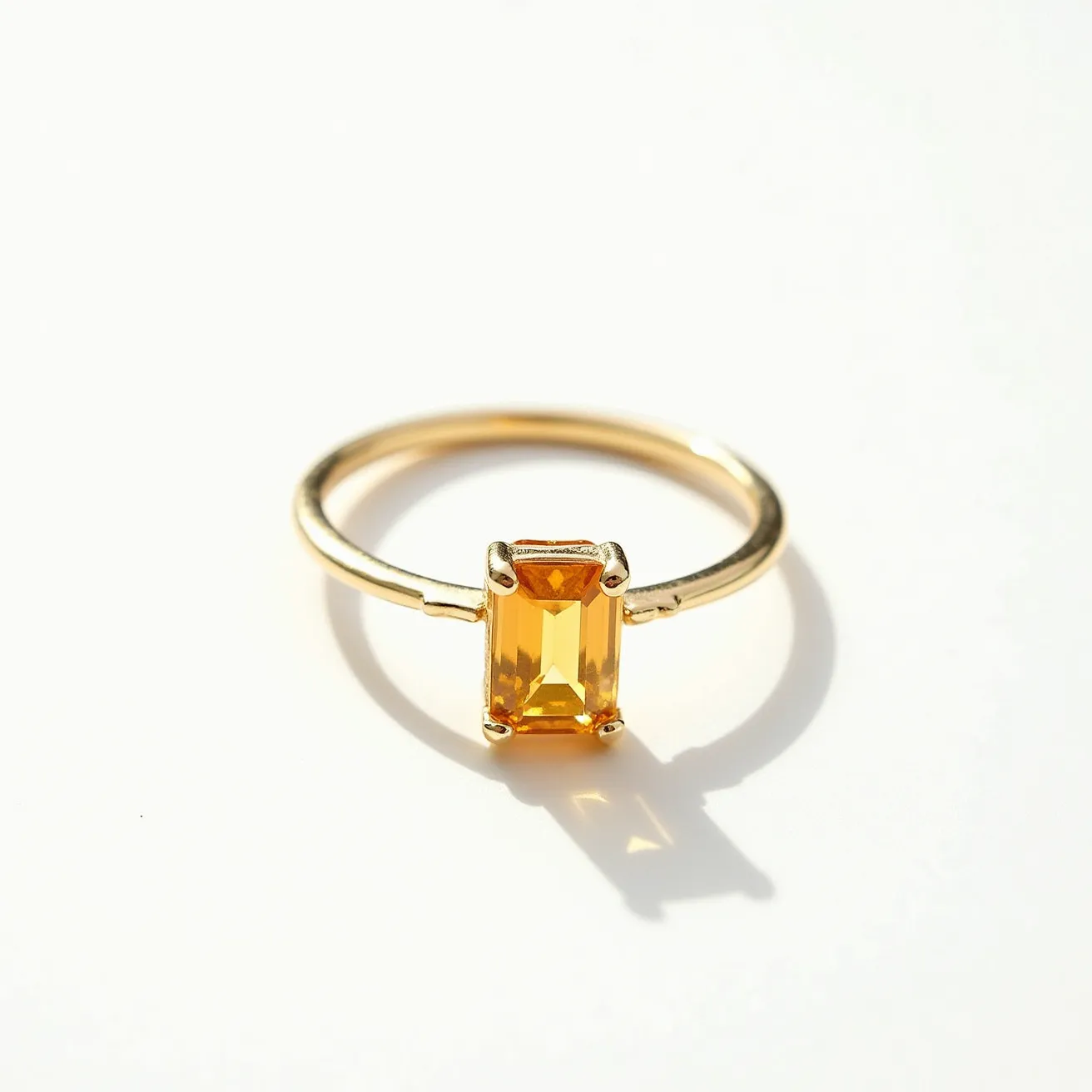 This November birthstone ring features a vibrant, rectangular-cut citrine stone, known for its warm amber hue, prominently set in a classic four-prong setting. The prongs are crafted to securely hold the citrine, enhancing its natural brilliance and clarity. The band of the ring is made of polished gold, adding a complementary richness to the gemstone. The overall design is elegant and straightforward, showcasing the beauty of the birthstone itself without any additional attachments or embellishments.