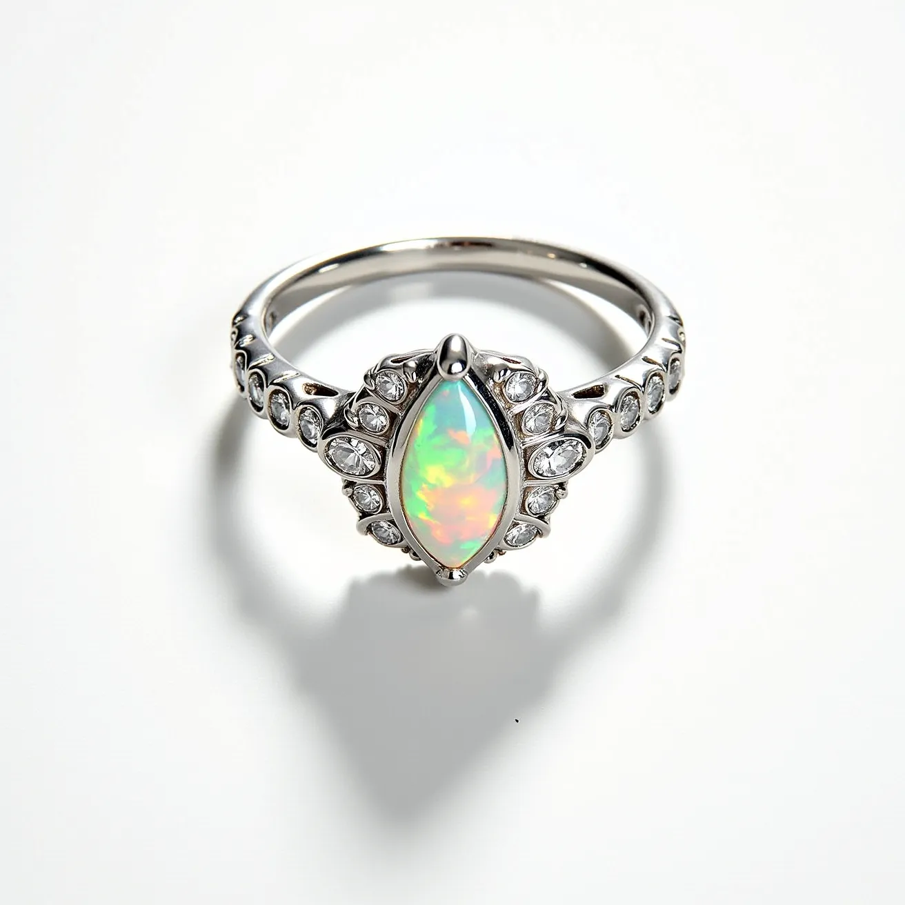 This opal engagement ring features a stunning marquise-cut opal as the centerpiece, renowned for its vibrant play of colors. The opal is set in a beautifully crafted prong setting, which secures the gem while allowing it to catch the light from all angles. Surrounding the central opal are numerous round-cut diamonds, accentuating the opal's brilliance and adding a touch of classic elegance. The band of the ring appears to be made of a high-quality metal, possibly white gold or platinum, complementing the gemstones with its sleek and polished finish. The design is both intricate and harmonious, offering a blend of modern sophistication and timeless charm.