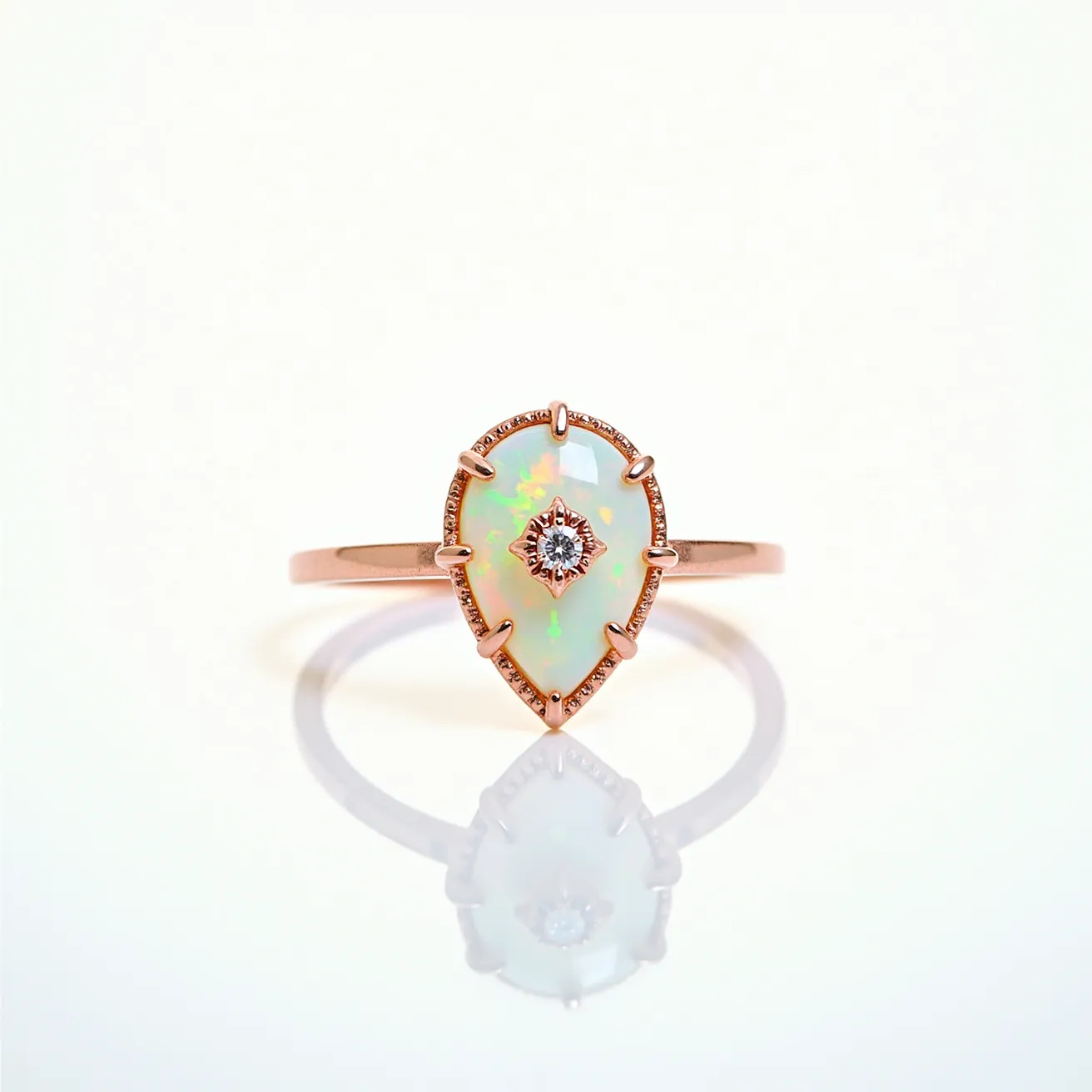 This opal ring features a stunning teardrop-shaped opal as the center stone, exhibiting a vibrant play of colors characteristic of high-quality opals. The opal is set in a rose-gold mount, which complements the stone’s iridescence. Surrounding the opal is a delicate halo of small, round-cut diamonds, enhancing its luminescence and adding elegant sparkle. The ring is crafted from a smooth, polished band in matching rose gold, providing a cohesive look. The opal is held securely in place by a series of prongs extending from the halo, ensuring both stability and a stylish design.