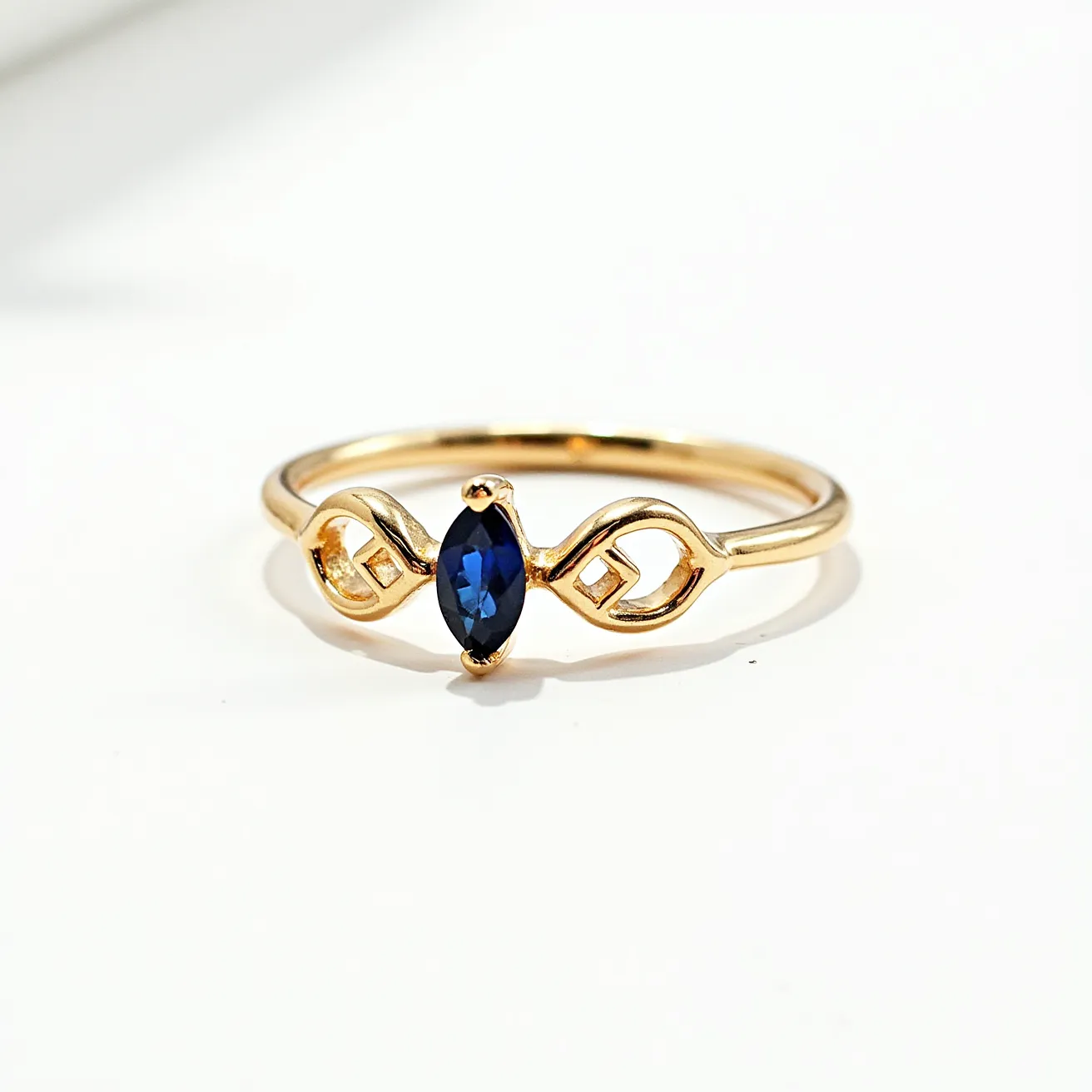 This open ring showcases an elegant design featuring a sleek band, likely made of gold. At the center, it is adorned with a deep blue marquise-cut gemstone, possibly a sapphire, secured by a four-prong setting. The band is gracefully shaped into a symmetrical pattern flanking the stone, adding to its sophisticated appearance. There are no clasps or additional attachments, emphasizing the ring's minimal yet striking design.