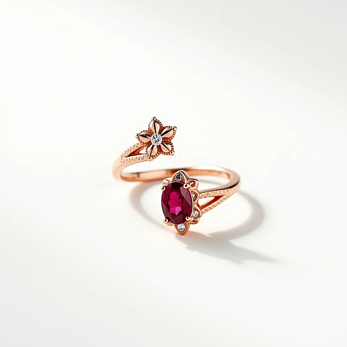 This open ring is crafted from rose gold, featuring an elegant and intricate design. One end of the ring is adorned with a floral motif set with a small, round, brilliant-cut diamond at its center, enhancing its delicate charm. On the opposite end, a striking oval-cut red gemstone, likely a ruby or garnet, is set within a decorative bezel embellished with smaller diamond accents, adding a touch of sophistication. The ring's design includes split shanks embellished with milgrain detailing, contributing to its overall vintage allure. The absence of a traditional clasp emphasizes its contemporary open-ended style.