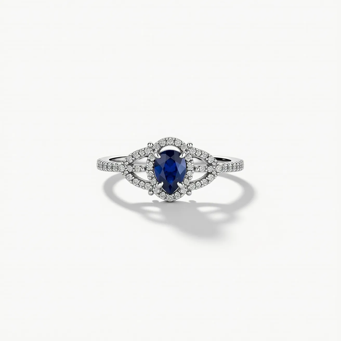 This open ring features a delicate band likely made of white gold or platinum, adorned with a stunning pear-shaped blue sapphire as its centerpiece. The sapphire is encircled by a halo of small, round-cut diamonds, enhancing its brilliance and creating a captivating contrast. The setting is likely a prong or claw setting, securing the sapphire while allowing maximum light to pass through for improved sparkle. The openwork design on the band adds elegance and intricacy, with additional small diamonds set along the band for added shimmer. This ring embodies both sophistication and timeless beauty.