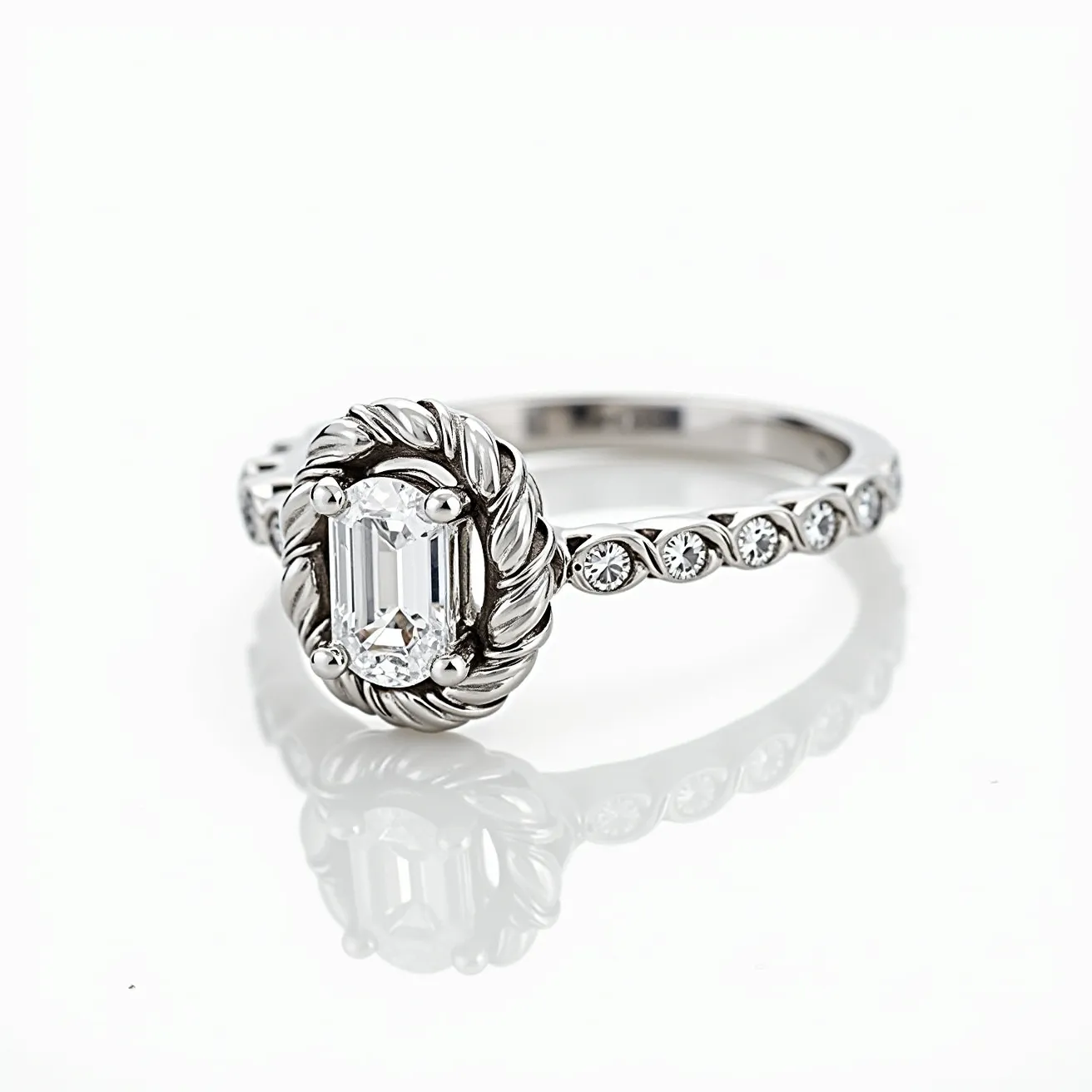 This oval engagement ring features a central emerald-cut diamond, elegantly set with four prongs in a beautifully detailed halo setting, which showcases intricate rope-style metalwork around the gemstone. The ring band is crafted from a lustrous metal, likely platinum or white gold, and is adorned with round diamonds set along the shank, enhancing its brilliance. The side stones are bezel-set, adding additional sparkle and complementing the timeless elegance of the centerpiece. The careful design and arrangement of the stones and setting highlight a sophisticated and classic style while ensuring the secure placement of each gem.