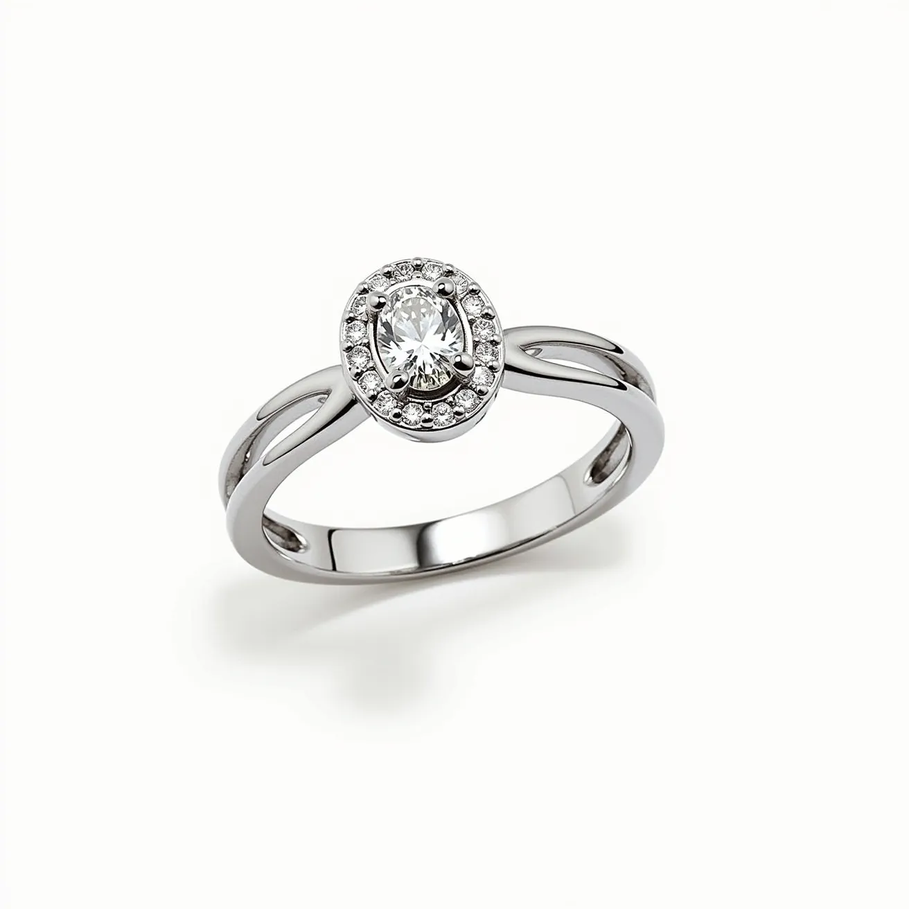 This oval engagement ring features a central oval-cut diamond, elegantly surrounded by a halo of smaller round diamonds, enhancing its sparkle and appeal. The setting is crafted from a polished white metal, likely white gold or platinum, providing a sleek and modern look. The ring's band is designed with an open split-shank style, adding a unique architectural element. The central diamond is secured with a four-prong setting, ensuring its stability while maximizing its brilliance. The ensemble of materials and design elements creates a sophisticated and timeless aesthetic.