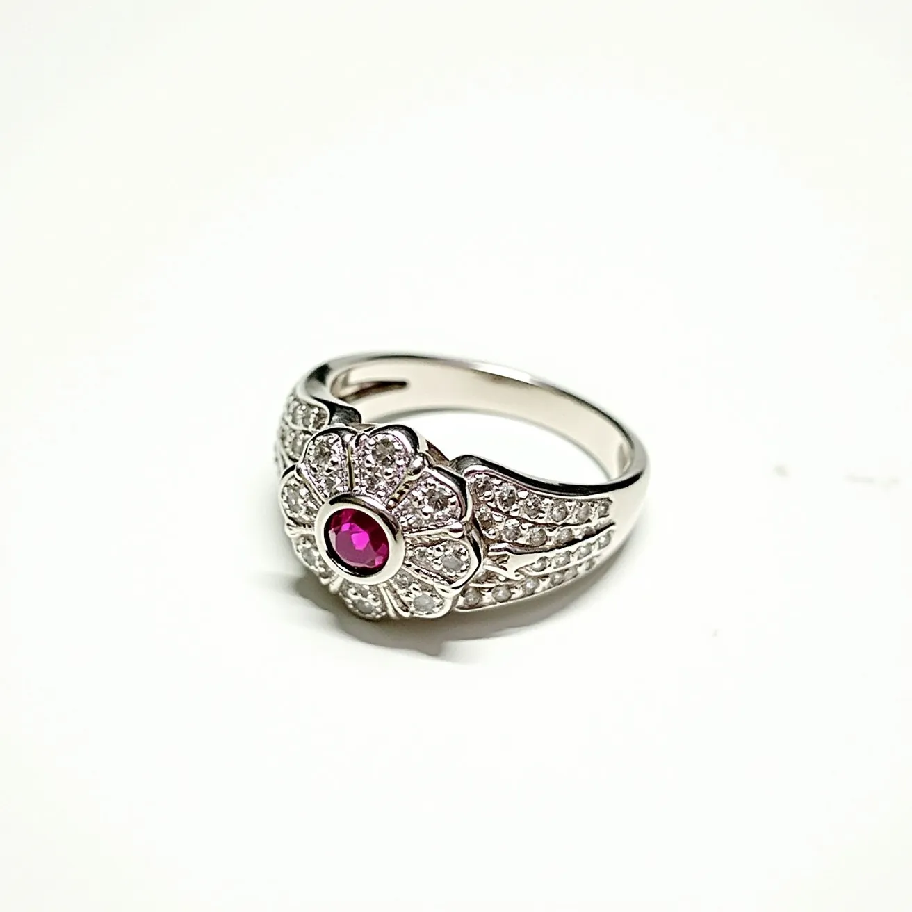 This pave diamond ring showcases a striking design, featuring a central round-cut ruby at its focal point, set in a bezel setting that accentuates its vibrant hue. Surrounding the ruby, numerous smaller diamonds are intricately set in a pave style, creating a sparkling backdrop that enhances the overall brilliance of the piece. The band appears to be crafted from a white metal, likely platinum or white gold, which complements the stones and adds to the ring's elegance. The combination of pave diamonds and the bold ruby creates a visually captivating contrast, embodying both luxury and sophistication.