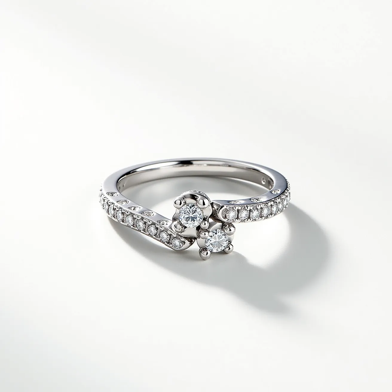 This pave diamond ring features a beautifully intertwined band, showcasing a delicate design studded with small round-cut diamonds set in a pave style. At the center, two larger round brilliant diamonds take prominence, each secured by four prongs, adding a dynamic focal point to this elegant piece. The band is crafted from a lustrous metal, likely white gold or platinum, providing a timeless backdrop for the sparkle of the diamonds. The prong and pave settings enhance the brilliance of the stones, making this ring a perfect blend of elegance and sophistication.