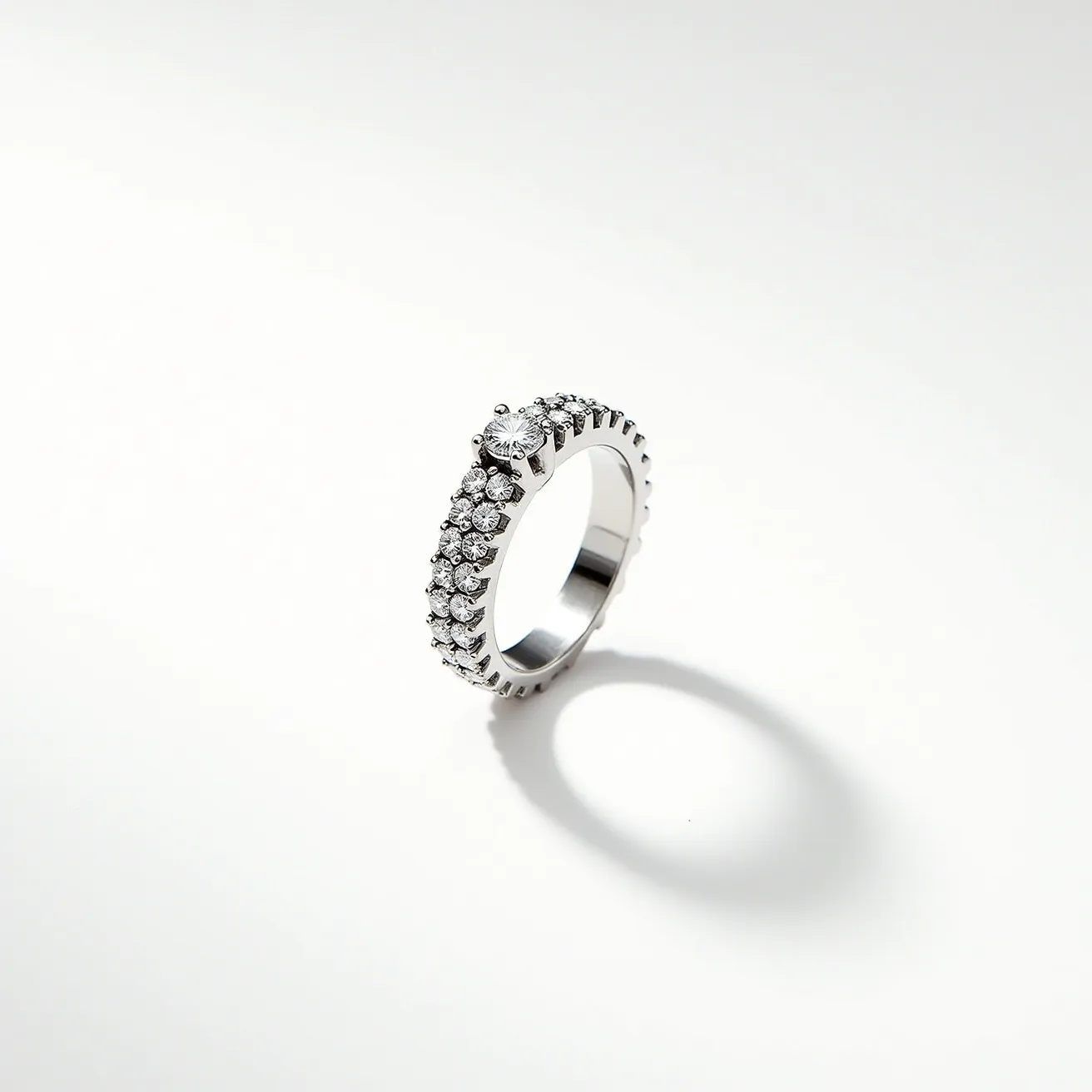 This pave ring is crafted from a polished metal band, likely platinum or white gold, adorned with a pattern of small round brilliant-cut diamonds that are closely set together, covering a significant portion of the surface in a glittering pave setting. The center stone is prominently set in a six-prong setting, likely also a round brilliant-cut diamond, enhancing its prominence and brilliance. The combination of the pave design and the prong-set center stone creates an elegant and timeless aesthetic, emphasizing the sparkle and clarity of the diamonds without other attachments or clasps.