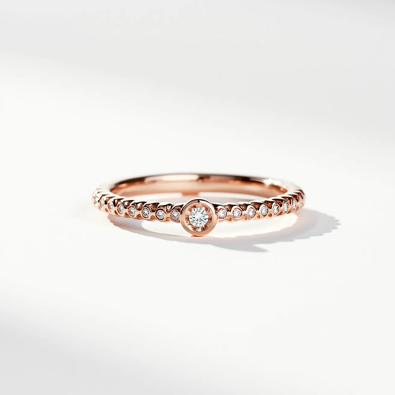 This pave ring is crafted from rose gold, featuring a central bezel-set round-cut diamond. Surrounding the central stone, smaller round diamonds are set into the band in a pave style, enhancing the ring's sparkle. The thin band and delicate settings give the ring an elegant and refined appearance, ideal for a minimalist yet luxurious look.