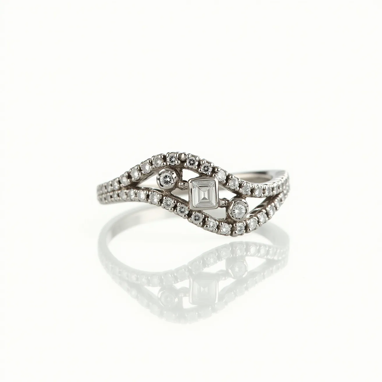 This pave ring features a sophisticated design crafted from a polished silver-toned metal, which forms an intricate, crisscrossing band. The band is adorned with multiple small, round-cut diamonds set closely together, creating a continuous sparkling effect typical of a pave setting. Central to the design is a prominent square-cut diamond, securely set to draw attention. Flanking the central stone are two round diamonds, each bezel set for added security and style. The overall effect is one of elegance and modernity, with the diamonds expertly positioned to reflect light from every angle.