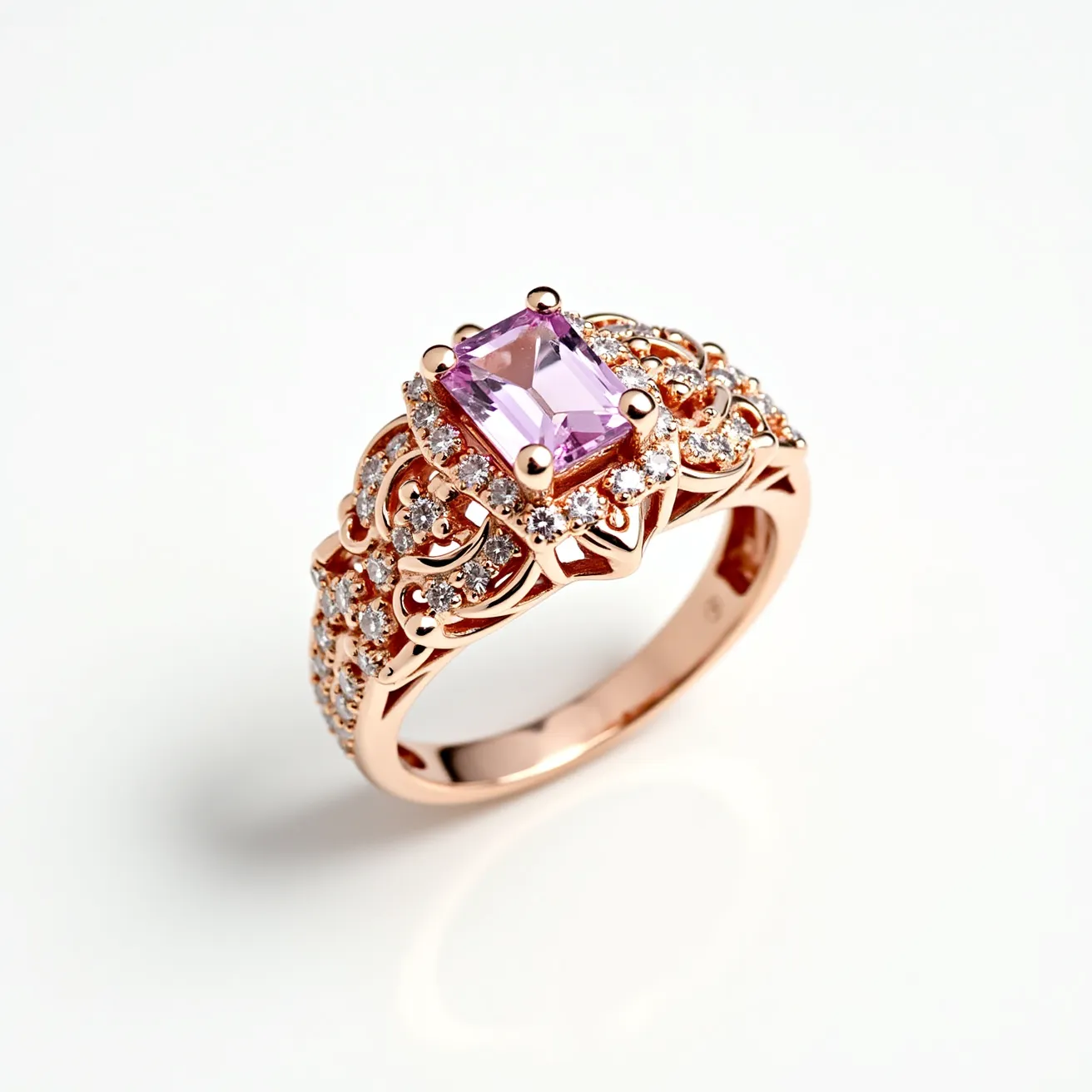 This pink diamond ring features an exquisite, rectangular-cut pink gemstone centrally set, likely a pink diamond or sapphire. The gemstone is held in place by four prongs and is beautifully accented by a series of smaller round diamonds that add sparkle and enhance the main stone's color. The ring is crafted from rose gold, which complements the pink hue of the central stone and provides a cohesive, luxurious look. The band showcases an intricate, ornate design with additional diamonds embedded throughout, lending a vintage and elegant aesthetic to the piece.