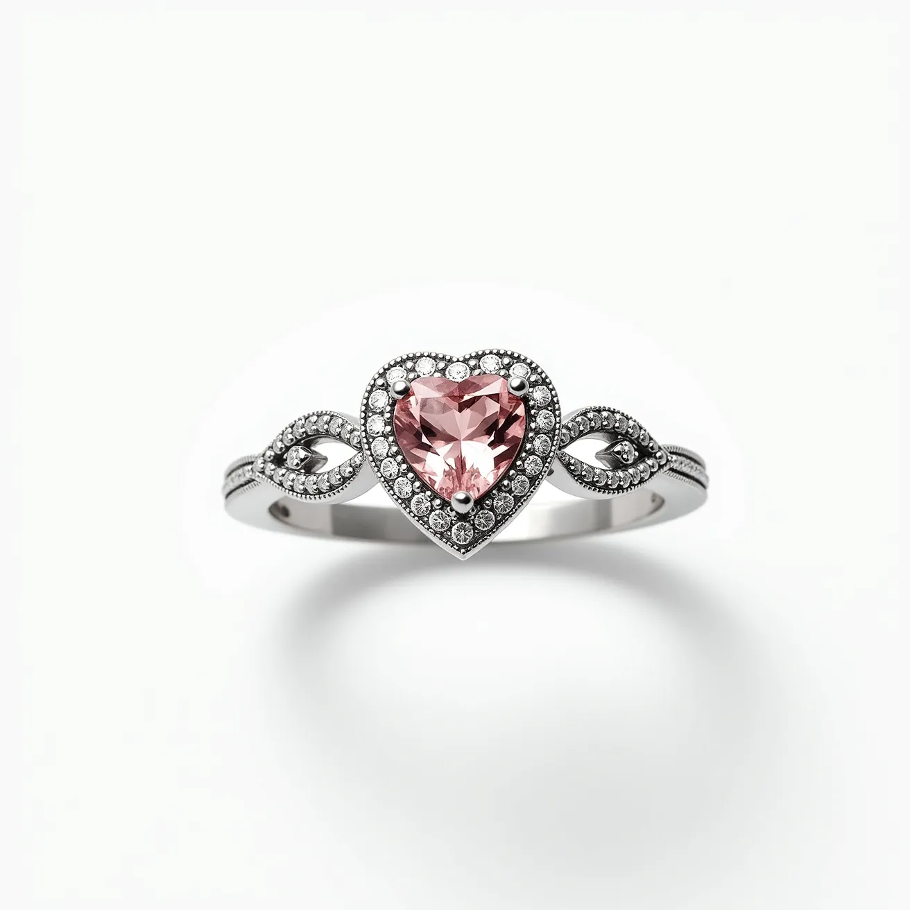 This pink heart ring features a stunning heart-shaped pink gemstone, likely a pink sapphire or morganite, set at its center. The stone is encircled by a halo of smaller white stones, possibly diamonds, which enhance its brilliance. The band is crafted from a reflective metal, such as white gold or platinum, and is elegantly designed with intricate, symmetrical patterns that incorporate additional small white stones. The arrangement of these elements adds to the overall elegance and sophistication of the piece.