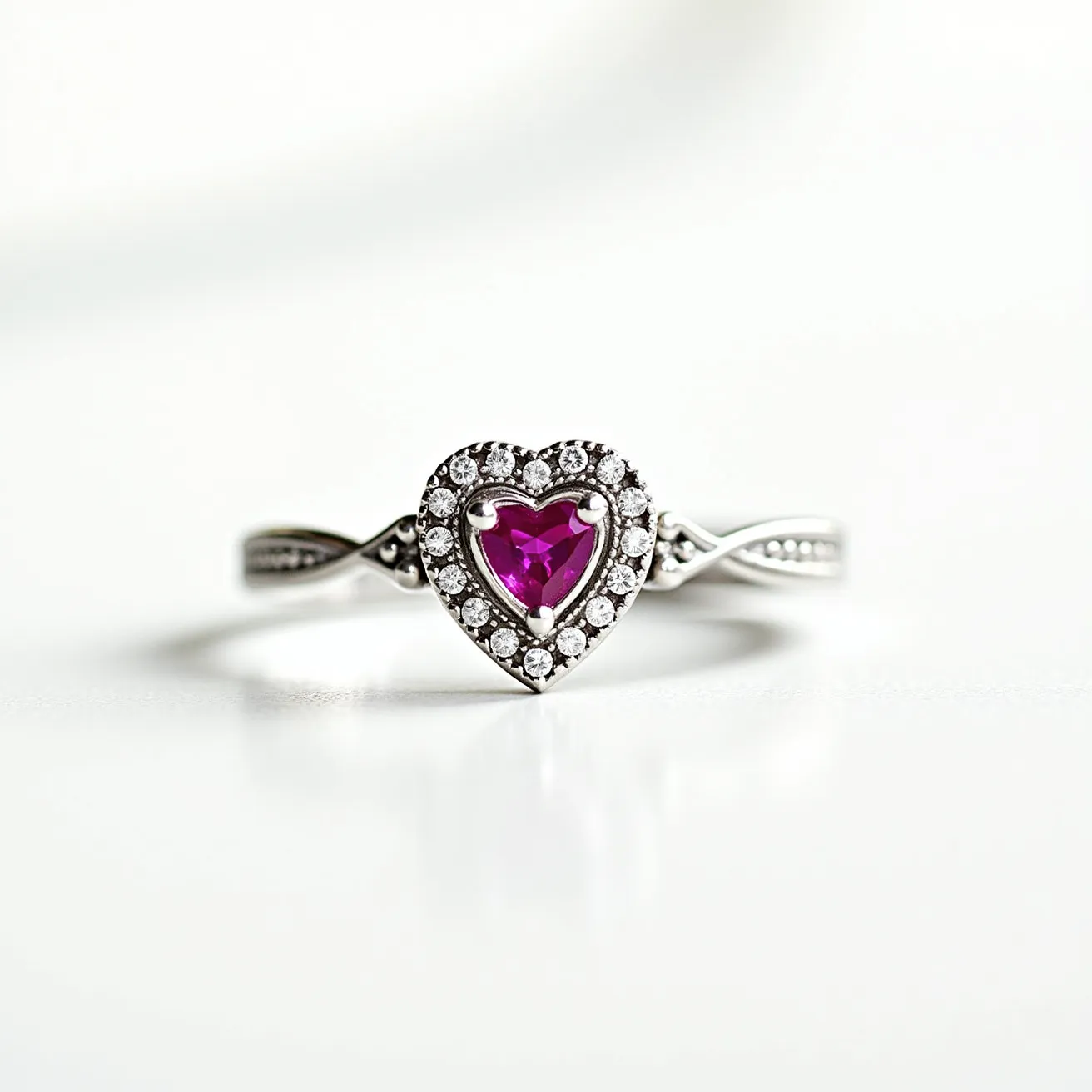 This pink heart ring features a vibrant pink heart-shaped gemstone set at its center, surrounded by a halo of small, sparkling white stones. The pink gemstone is cut to reflect light attractively, enhancing its vivid color. The setting for the pink stone appears to be secured by prongs, which hold it in place securely, while the surrounding stones are likely set closely to provide a seamless halo effect. The band of the ring is crafted from a presumably metallic material with subtle detailing that adds elegance to the design. The delicate design suggests an emphasis on highlighting the central heart-shaped stone, making it a focal point of the piece.