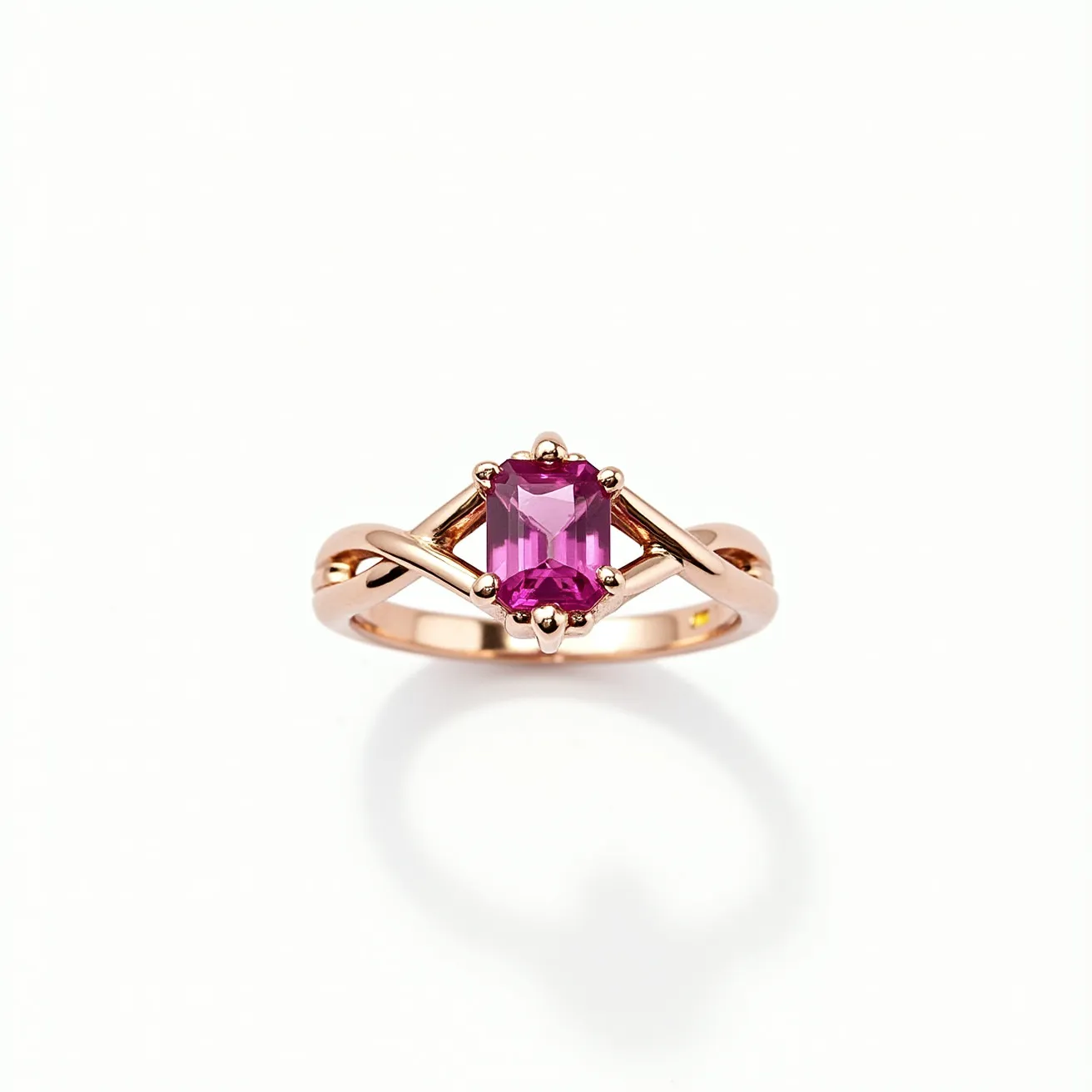 This pink sapphire ring features a vibrant, emerald-cut pink sapphire at its center, which is elegantly set with a four-prong setting. The band, crafted from a lustrous rose gold, gracefully intertwines as it approaches the gemstone, adding a touch of sophistication to the design. The ring's simplicity highlights the striking color and cut of the sapphire, making it a timeless piece suitable for various occasions. The secure setting and seamless band provide both beauty and durability in its construction.