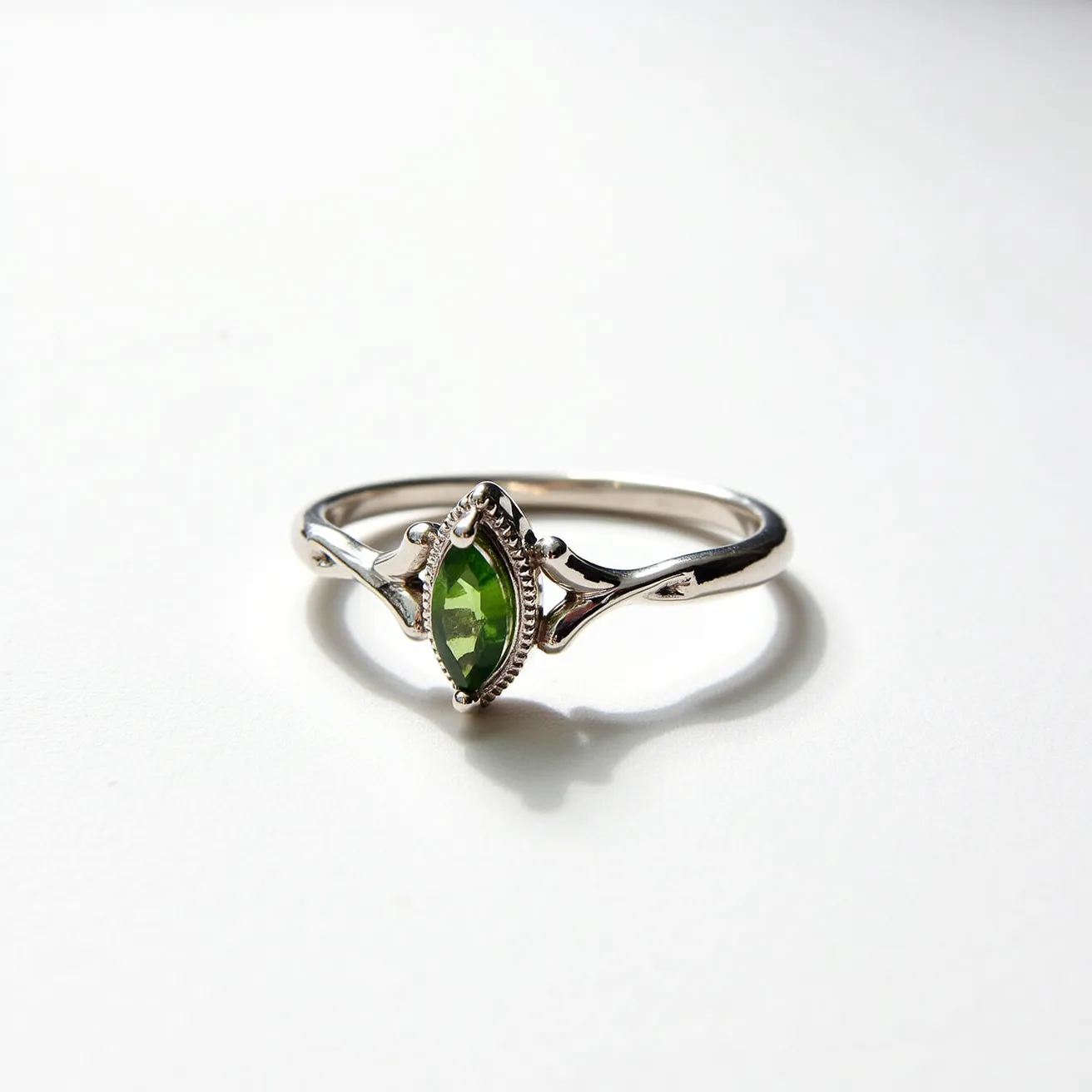 This prasiolite ring features a marquise-cut green prasiolite gemstone, elegantly set in a bezel setting with intricate detailing around the stone. The band, likely made of polished sterling silver, showcases a delicate and graceful design that complements the central stone. The setting is designed to securely hold the prasiolite, enhancing its natural beauty with subtle elegance. The craftsmanship of the ring reflects a balance between vintage charm and modern sophistication.