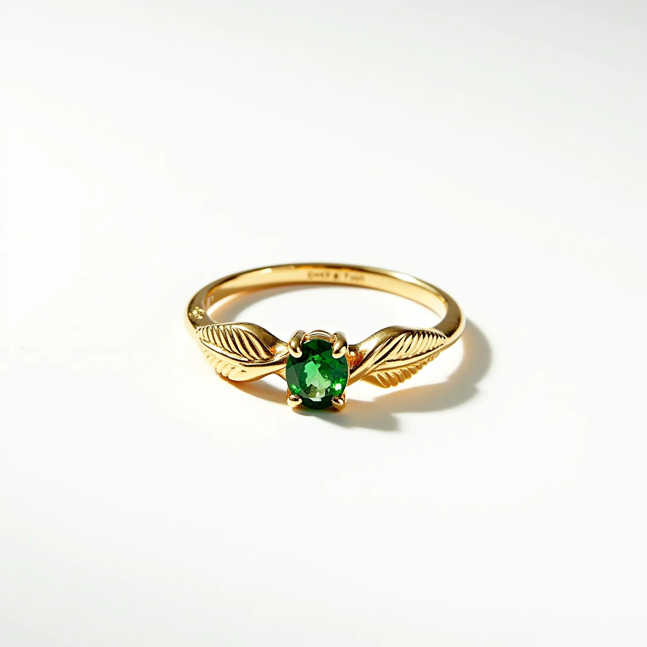 This prasiolite ring features a vibrant green oval-cut prasiolite gemstone set in a prong setting, which elegantly highlights the stone. The band is crafted from a yellow gold material, adorned with intricate leaf motifs on either side of the gemstone, adding a nature-inspired touch to the design. The smooth, polished finish of the band enhances the overall elegance and sophistication of the piece, making it a striking accessory for any occasion.