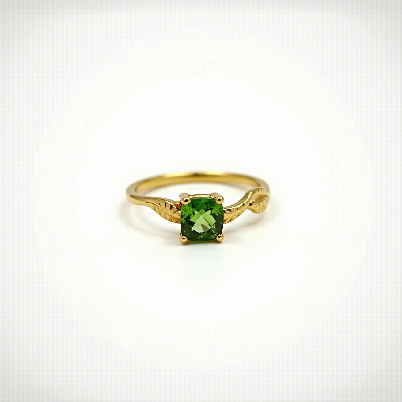 This prasiolite ring features a captivating square-cut green prasiolite gemstone set in a classic four-prong gold setting. The band of the ring is crafted from polished gold and showcases intricate leaf-like detailing on either side of the gemstone, enhancing its elegant and nature-inspired design. The prasiolite is securely attached to the band, allowing it to be displayed prominently as the focal point of the piece. The prasiolite's subtle green hue combined with the warm gold tones of the band creates a harmonious and refined aesthetic.