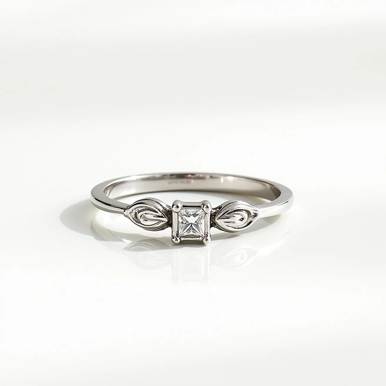 This promise ring features a sleek design crafted from a shiny metal, likely white gold or silver, given its reflective and polished appearance. At its center, a square-cut gemstone, resembling a princess cut, is secured in a bezel setting, adding a touch of elegance to the piece. On each side of the central stone, delicate marquise-shaped details extend from the band, enhancing its aesthetic appeal with a subtle, intricate pattern. The band itself is slender and smooth, emphasizing the central design and providing a minimalist yet elegant look without any additional clasps or attachments.