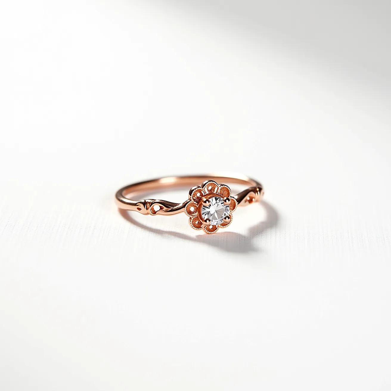 This promise ring features a delicate rose gold band with intricate detailing along the shank, exemplifying elegance and craftsmanship. Its centerpiece is a round, brilliant-cut gemstone, likely a diamond, held securely in a classic prong setting designed to maximize the stone's brilliance. The gemstone is surrounded by a floral-inspired halo, which enhances its beauty and adds a touch of vintage charm. The band’s slender design, combined with the prominent central gem, makes this ring a beautiful symbol of commitment.