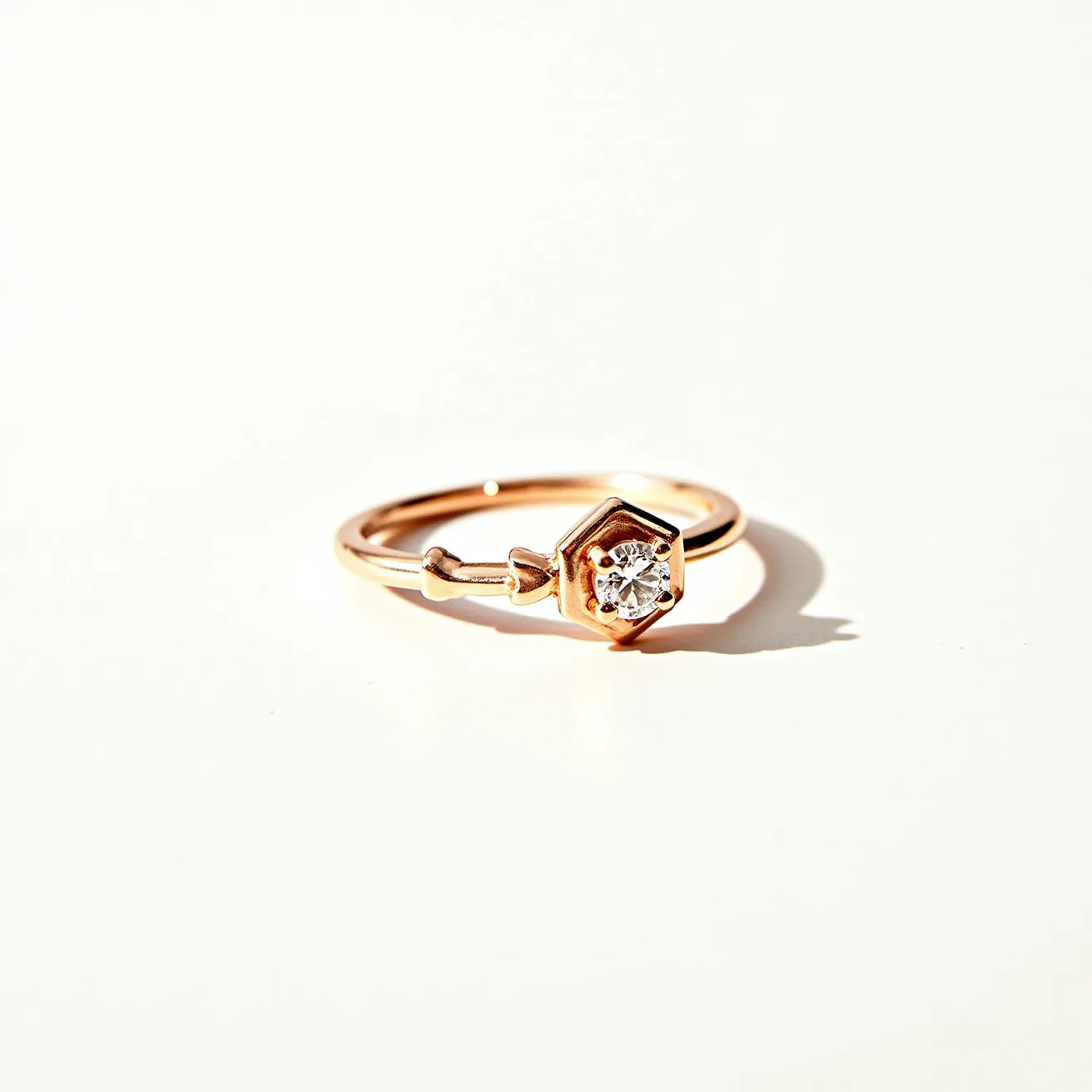 This promise ring features a delicate and elegant design crafted from rose gold, which provides a warm and luxurious appearance. At the center, there is a sparkling round-cut diamond set within a unique hexagonal bezel setting that adds a modern twist to the classic solitaire style. The band includes a subtle arrow detail, enhancing the romantic symbolism often associated with promise rings. The overall design is cohesive and thoughtfully constructed, emphasizing simplicity and sophistication without the need for additional clasps or attachments.