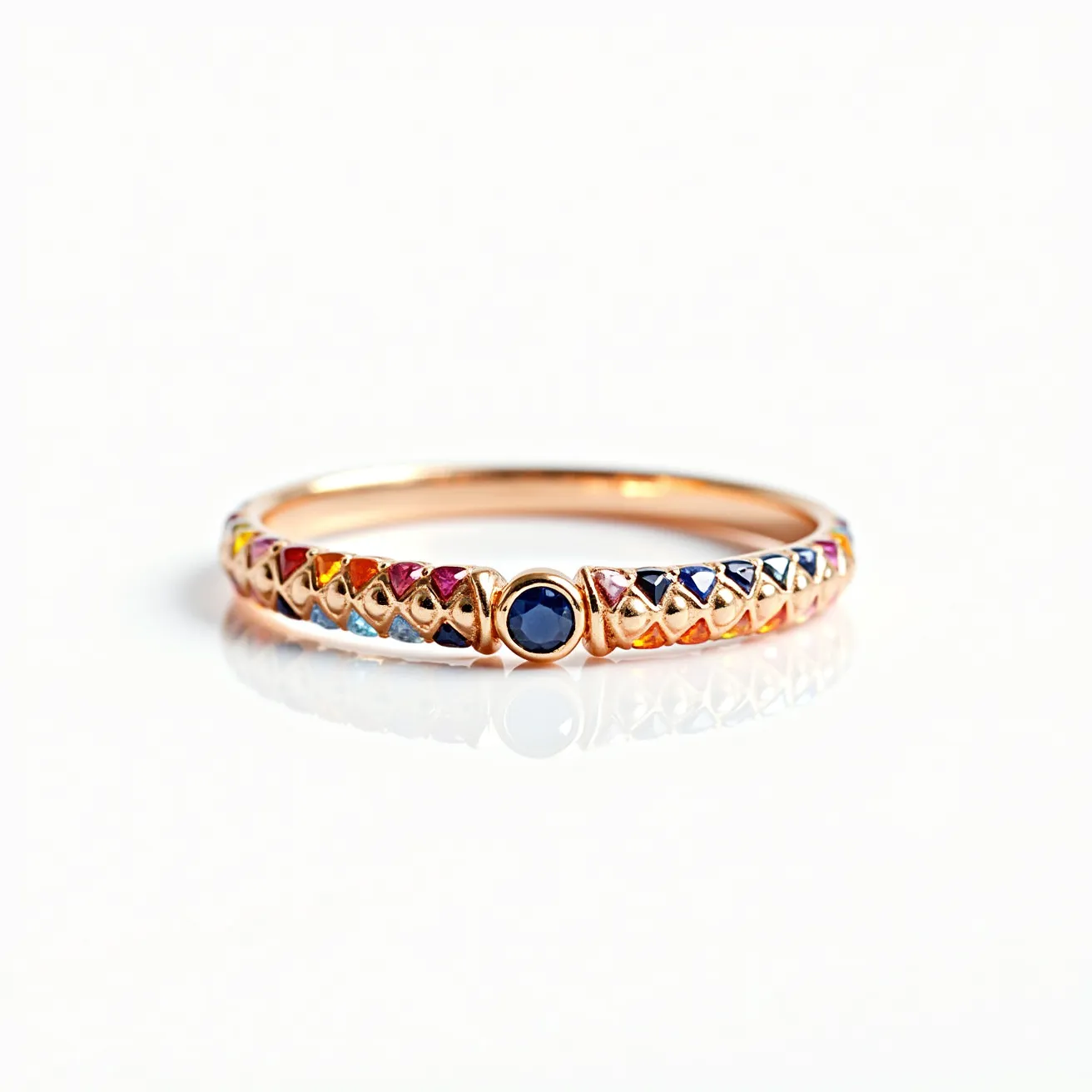 This rainbow ring features a delicate arrangement of colorful gemstones set in a gold band. The stones are round-cut and arranged in a sequence of vibrant colors, creating a captivating rainbow effect. At the center of the ring, there is a prominent round-cut blue gemstone, possibly a sapphire, set in a bezel setting that adds emphasis to its deep hue. The band showcases an intricate design with diamond-shaped elements that cradle each stone, enhancing the overall visual appeal. This finely crafted ring combines elegance and playfulness with its harmonious blend of materials and colors.