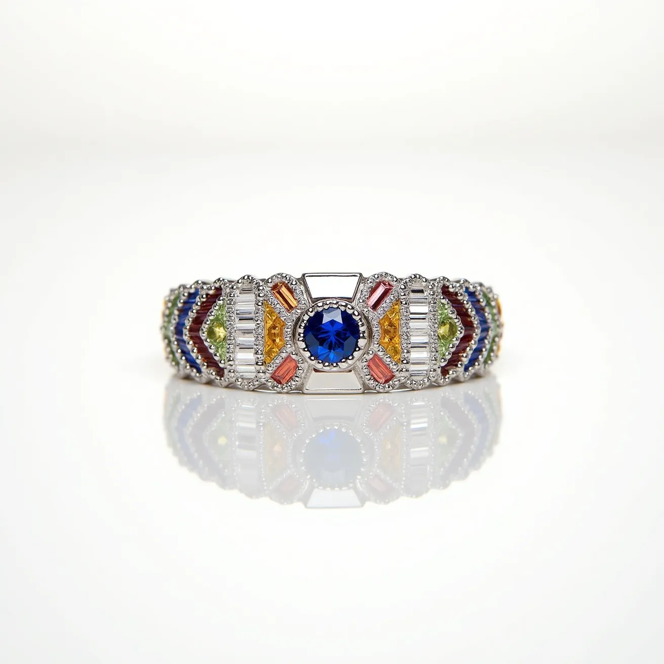 This rainbow ring features a stunning array of colorful gemstones set in a precious metal band. At the center, a round-cut blue sapphire is prominently placed, creating a striking focal point. Surrounding this center stone, baguette-cut diamonds are set in a detailed bezel setting, offering a brilliant contrast. Accentuating the sapphire are various gemstones in vibrant colors—orange, yellow, green, red, and blue—in different cuts, showcasing a spectrum reminiscent of a rainbow. The overall design combines symmetry and meticulous craftsmanship, with the gemstones securely set to highlight their natural brilliance.