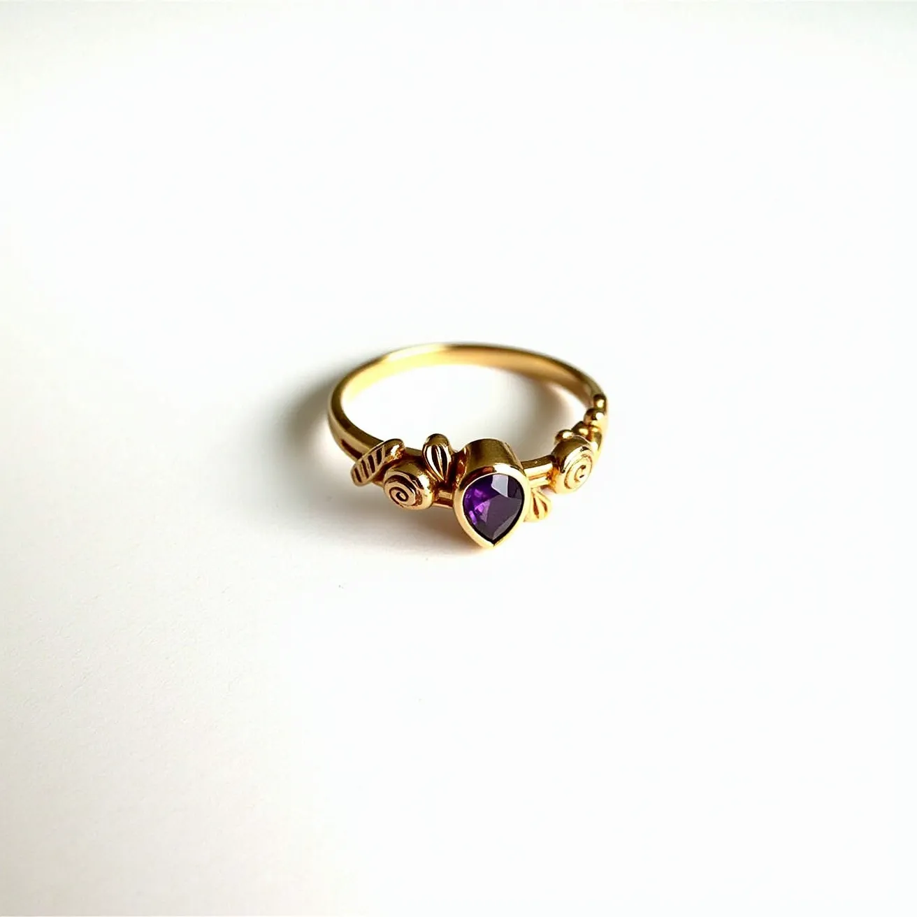 This Rapunzel promise ring features a gold band adorned with elegant, floral-like engravings. At its center, the ring showcases a purple, heart-shaped gemstone held in a bezel setting. The intricate details evoke a whimsical, fairy-tale theme, perfectly complementing the enchanting charm associated with Rapunzel.