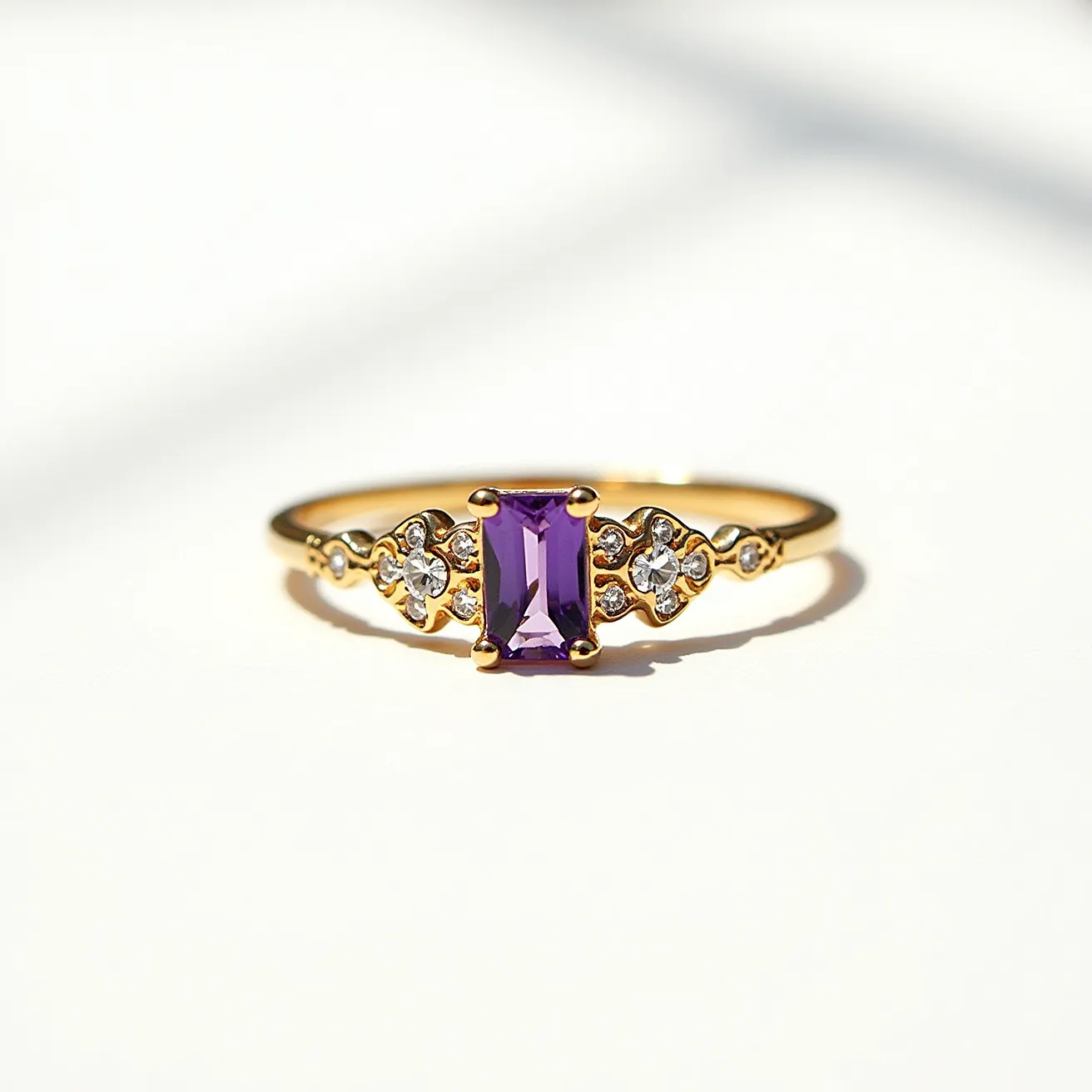 This Rapunzel promise ring features a delicate gold band with an elegant rectangular-cut purple gemstone at its center. The gemstone is set in a secure prong setting, allowing it to catch the light beautifully. On either side of the central stone, there are smaller clear round stones, which further enhance the ring's intricate design. These stones are set within a graceful, ornate pattern that adds a touch of sophistication. The overall design combines the charming elements of fairy tale elegance with a modern aesthetic.