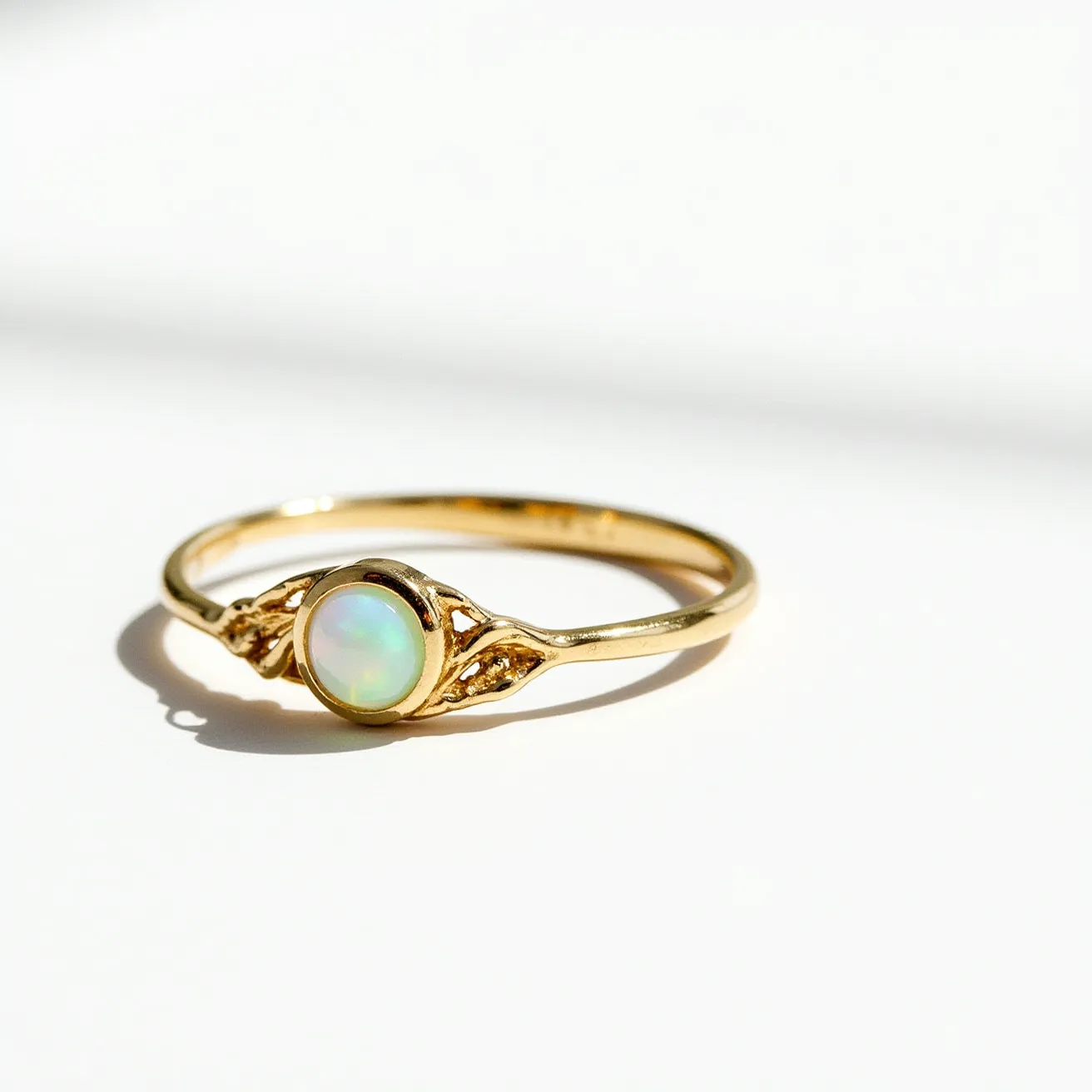 This ring band is crafted from gold and features a delicate design with a central opal gemstone. The opal, known for its iridescent play of colors, is cut in a cabochon style, which enhances its natural beauty. It is set in a bezel setting, securely surrounded by the metal. The band itself is slender, adding to the elegant and minimalist aesthetic of the piece.