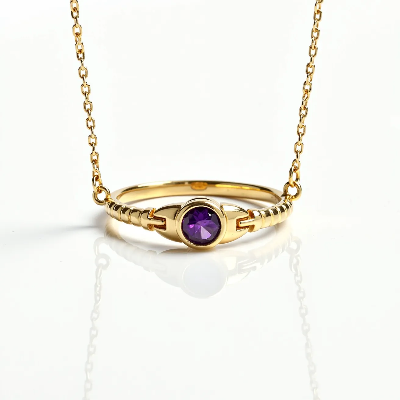 This ring necklace features a sleek gold band with a prominent purple gemstone at its center, likely an amethyst, displaying a round cut that allows for maximum brilliance and light reflection. The gem is securely held in a bezel setting that highlights its vibrant hue against the gold backdrop. The chain is composed of delicate, interlinked gold loops that complement the ring's design, suggesting an elegance and simplicity. A small jump ring connects the chain to the ring on either side, creating a seamless integration between the components and allowing the ring to serve as a pendant.