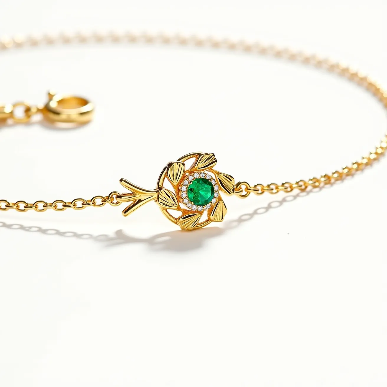 This ring necklace features a gold-toned chain with a decorative floral pendant at its center. The pendant houses a prominent round green gemstone, likely an emerald, which is surrounded by smaller clear stones that may be diamonds. The stones are set in a bezel, enhancing their brilliance and elegance. The necklace is equipped with a spring ring clasp, ensuring secure attachment and ease of wear. The floral motif adds a touch of nature-inspired sophistication, making it a striking piece of jewelry.