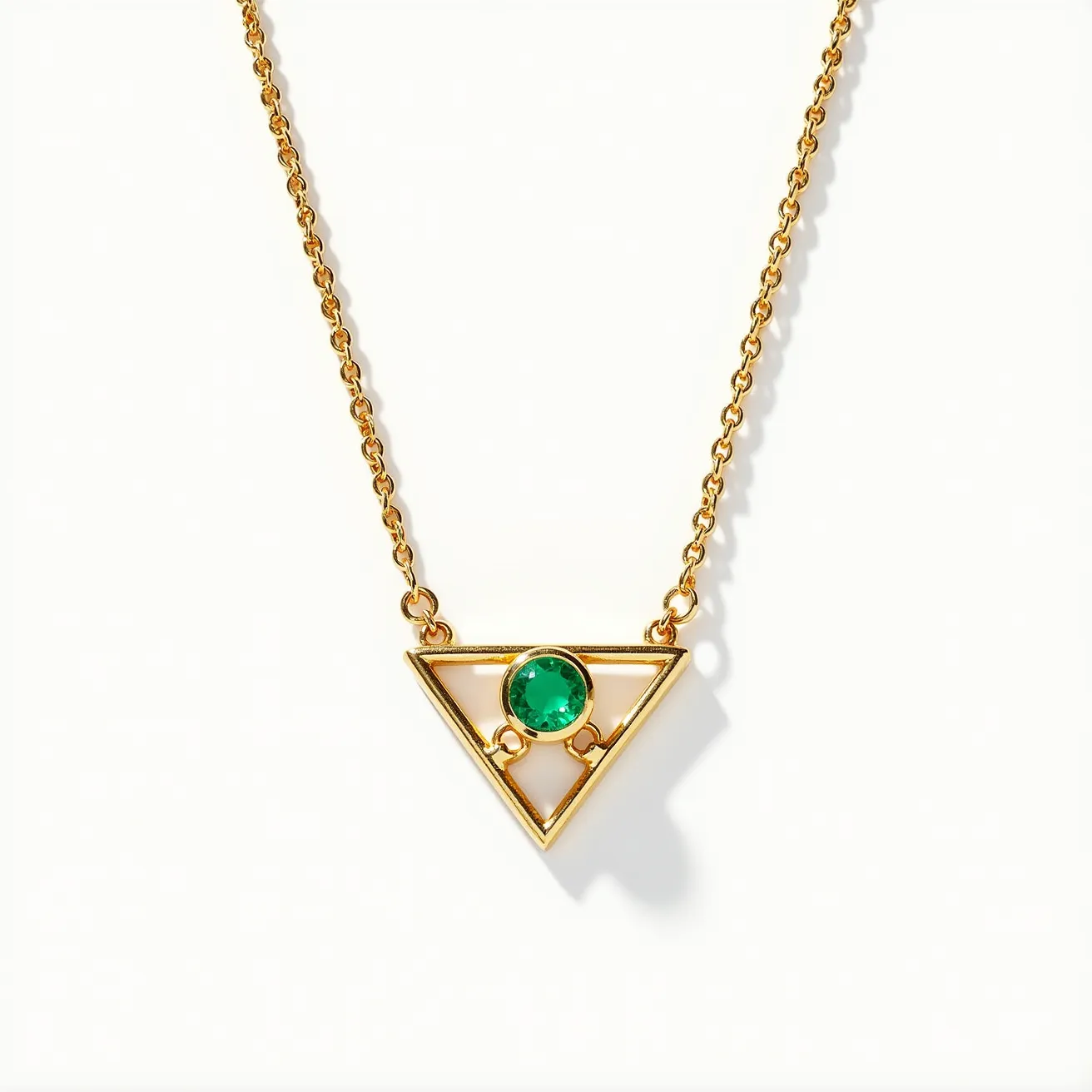 This ring necklace features a delicate gold chain that supports a triangular pendant. At the center of the pendant is a round, faceted green gemstone, securely held within a bezel setting, which enhances its brilliance and color. The geometric design of the triangle is modern and sleek, accentuated by the gold metal's warm luster. The necklace likely has a standard clasp for secure attachment. The combination of the gold and the vibrant green stone makes this a striking and elegant accessory.