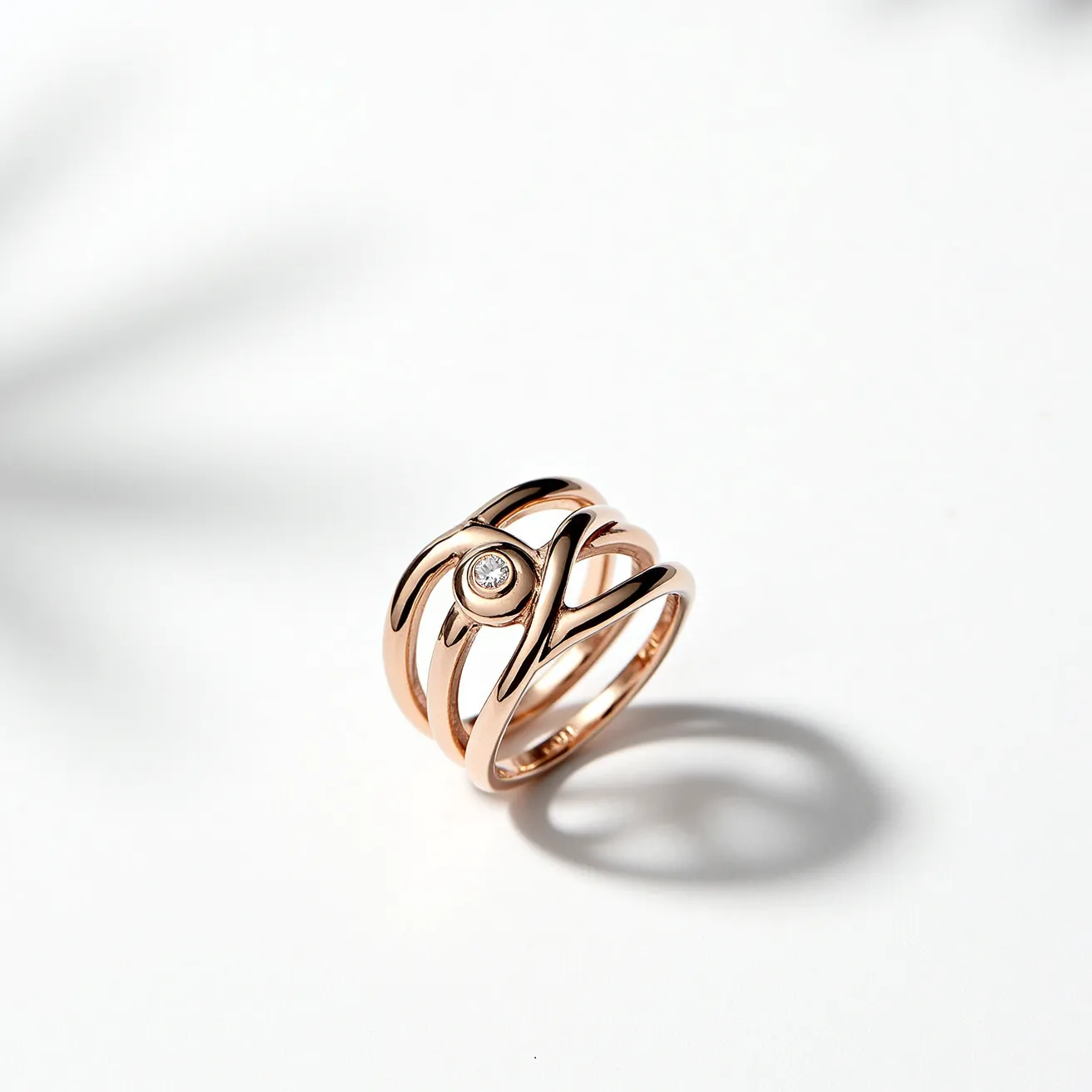 This rose gold ring features an elegant openwork design with multiple overlapping bands that create a distinctive, interwoven pattern. At the center of the design, there is a single round-cut diamond set in a bezel setting, adding a touch of sparkle and sophistication. The warm hue of the rose gold complements the brilliance of the diamond, creating a harmonious and stylish look. There are no visible clasps or additional attachments, highlighting the seamless and smooth craftsmanship of the ring.