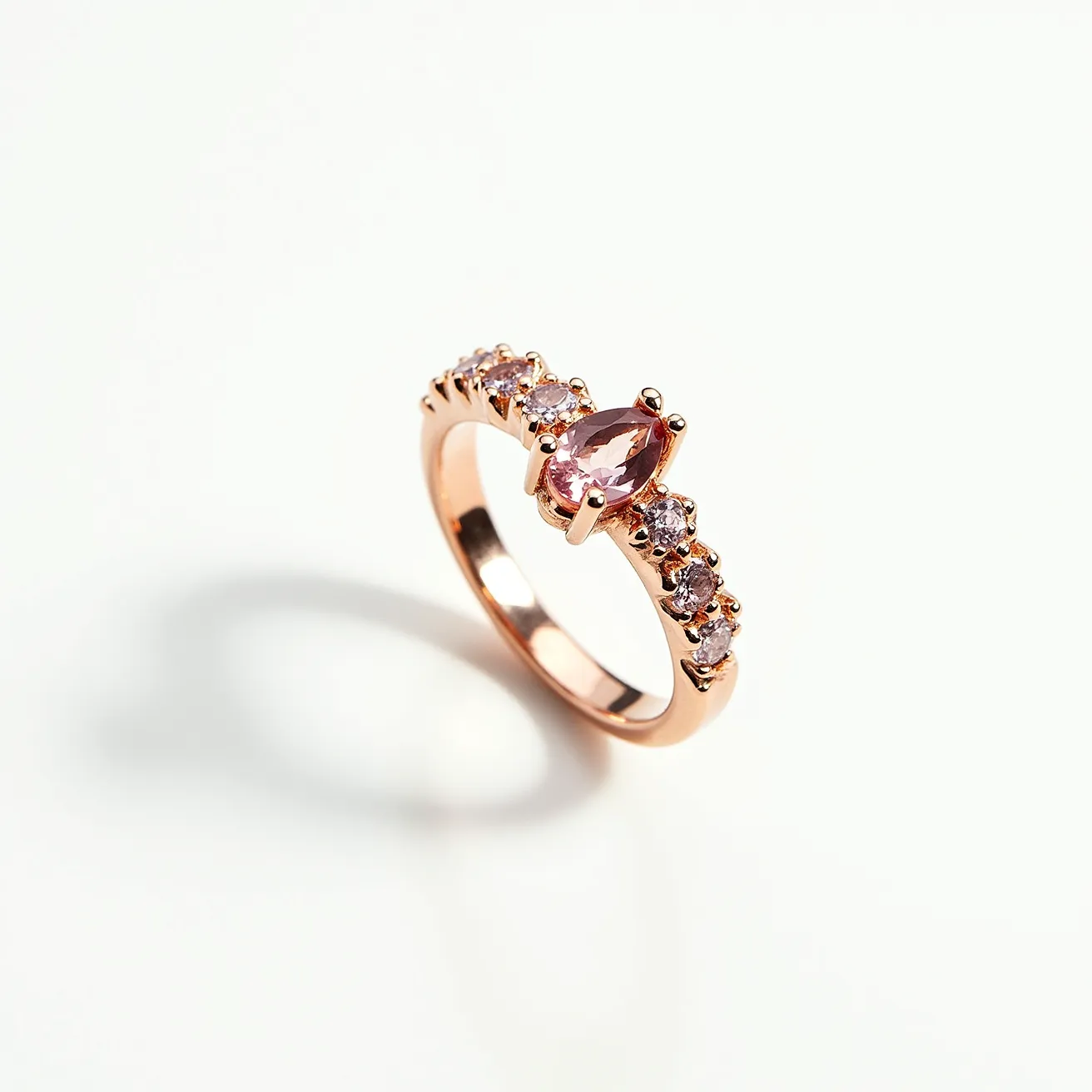 This rose ring is crafted from rose gold, featuring a polished band that highlights its luxurious finish. At its center is a marquise-cut pink gemstone, elegantly set in a prong setting that accentuates its elongated shape and sparkling facets. Flanking the central stone are smaller round-cut gems, each also securely set in prongs, adding to the ring's overall brilliance and cohesive design. The smooth band ensures a comfortable fit, seamlessly blending style with elegance.