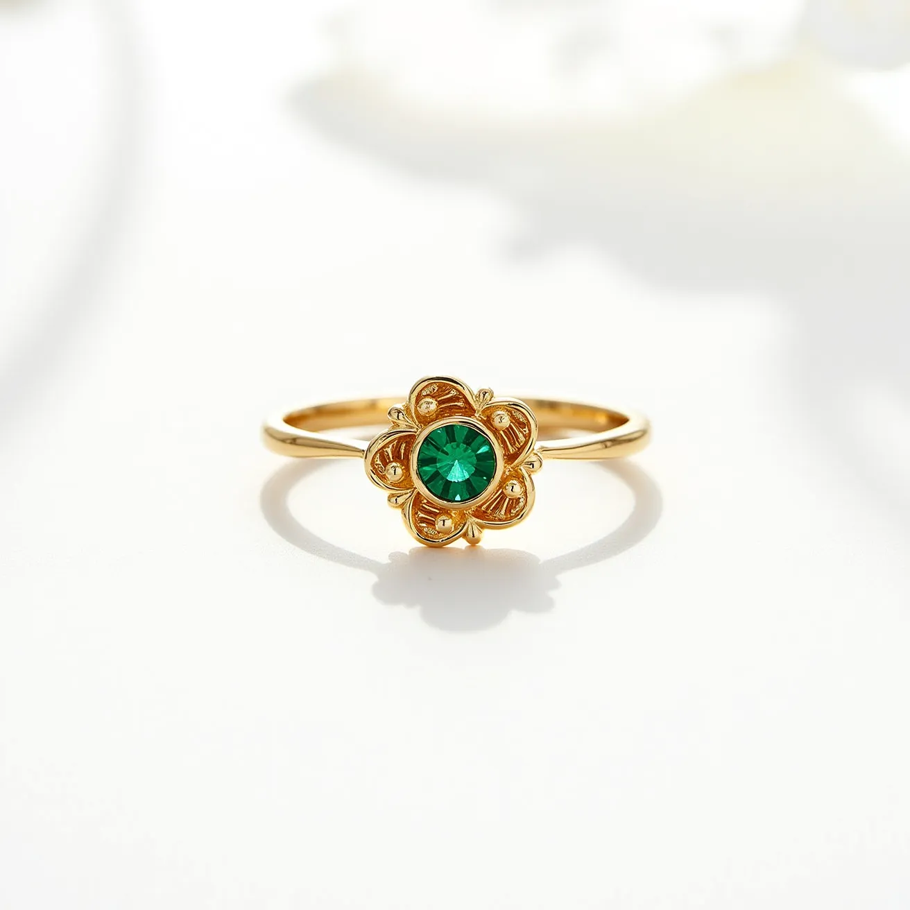 This rose ring features a delicate and elegant design composed of a gold band that elegantly supports a floral motif at its center. The centerpiece is adorned with a striking green gemstone, possibly an emerald or green crystal, cut in a round shape that catches the light beautifully. The gemstone is set in a bezel-style setting, securely cradled within a gold floral petal structure. The petals are finely detailed, adding an intricate touch to the overall design. There is no visible clasp or complex attachment, indicating the ring is a simple slip-on type, emphasizing its classic and refined appeal.